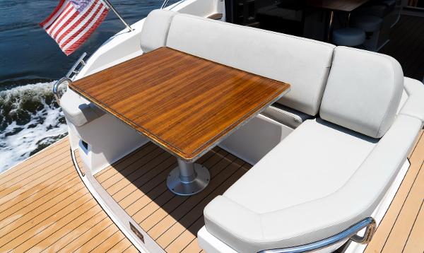 Luxury seating area on 2022 Bavaria SR41 yacht with wooden table and American flag.