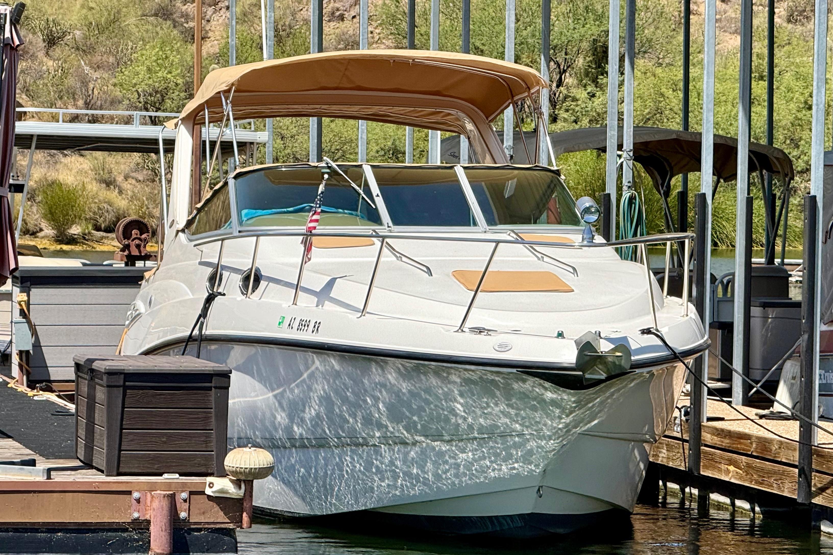 1999 Chaparral Signature 300 boat docked with tan canopy and American flag.