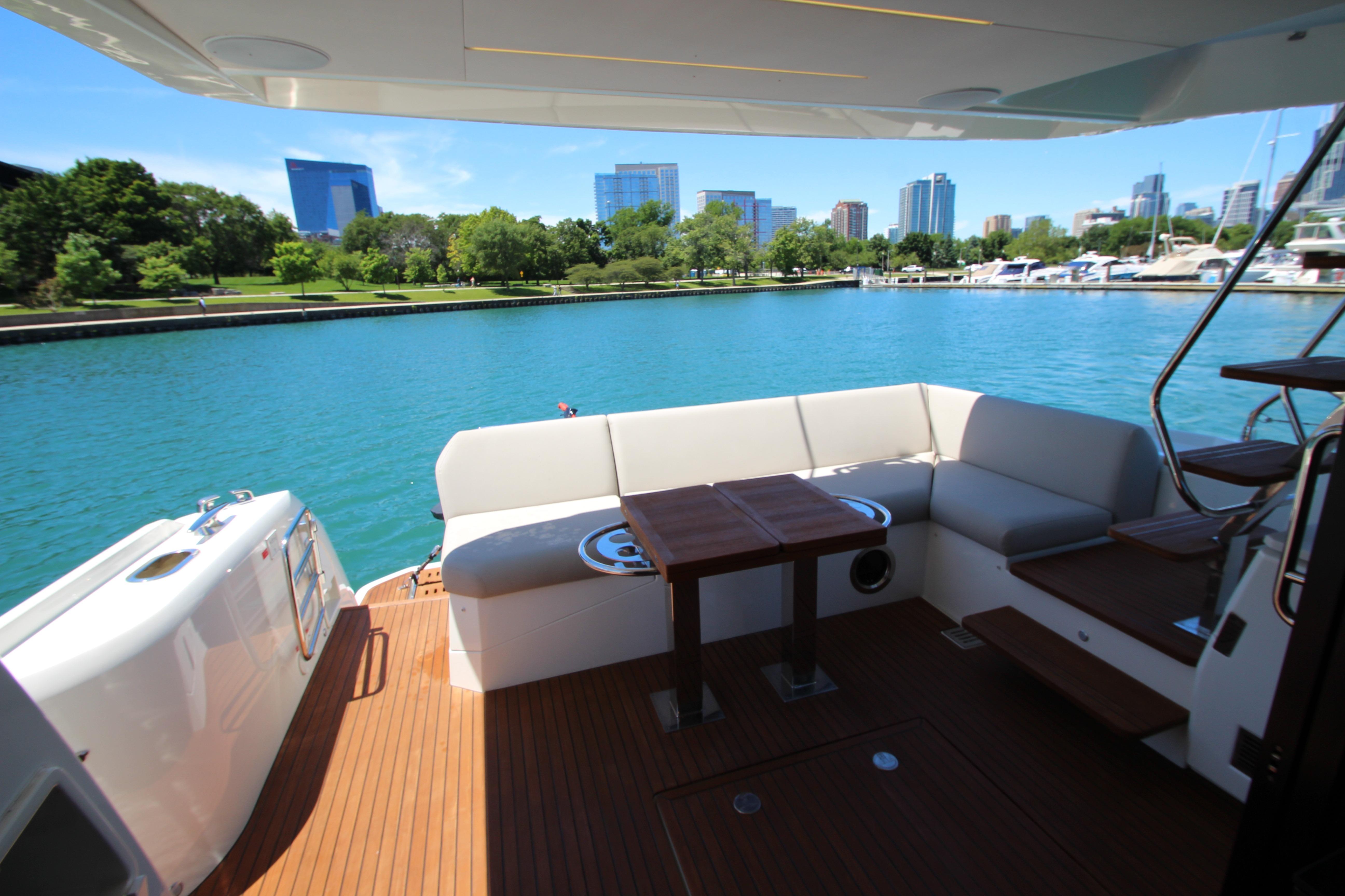 Luxurious 2022 Prestige 520 yacht deck with seating, overlooking a serene waterfront cityscape.