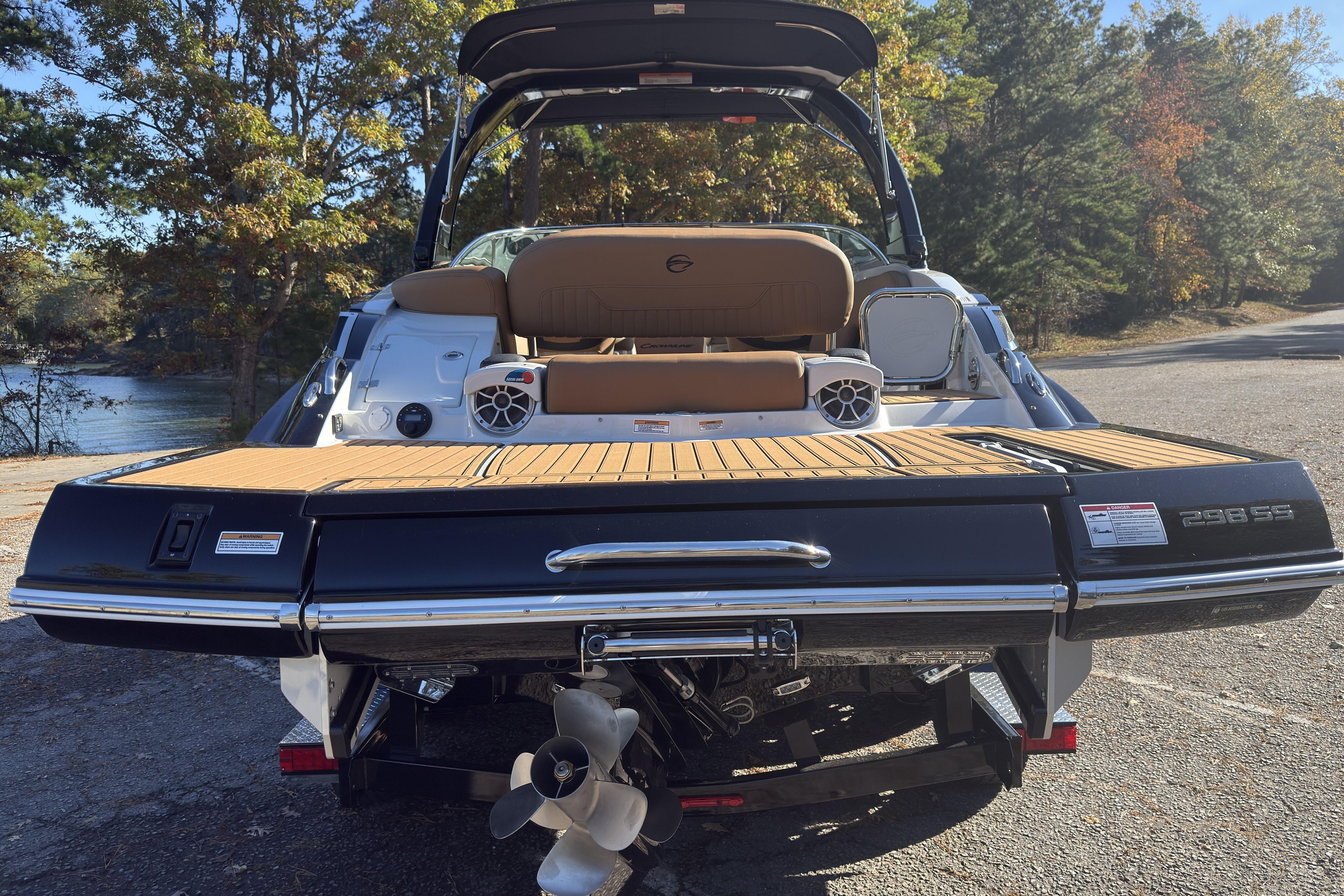 2026 Crownline 298 SS boat rear view with teak deck and speakers, parked near water.