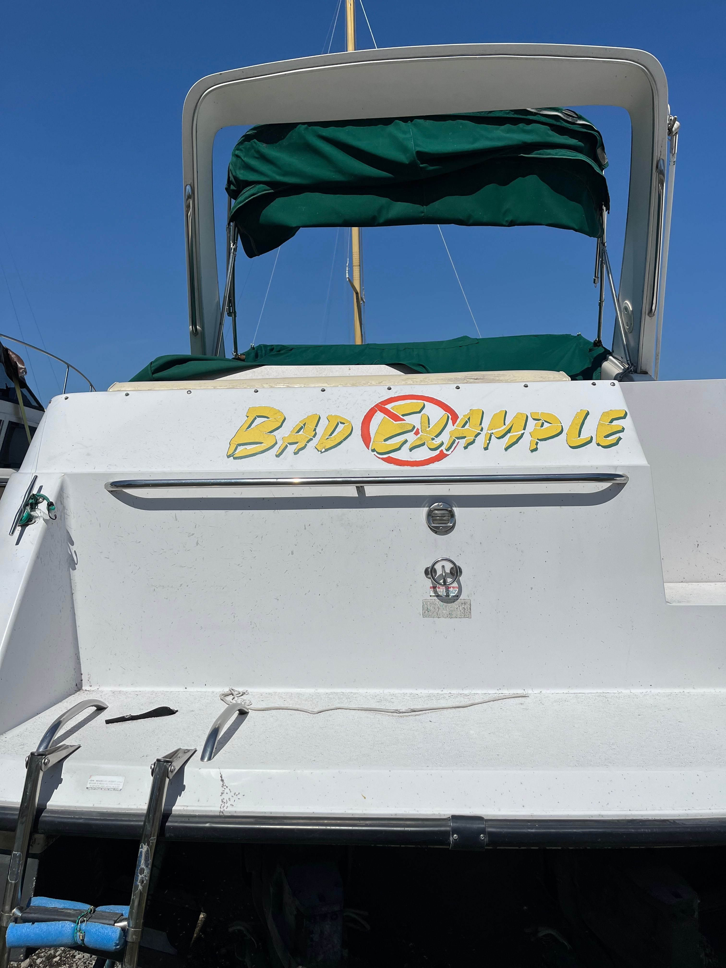 A boat with a green canopy and the words "Bad Example" on the stern.