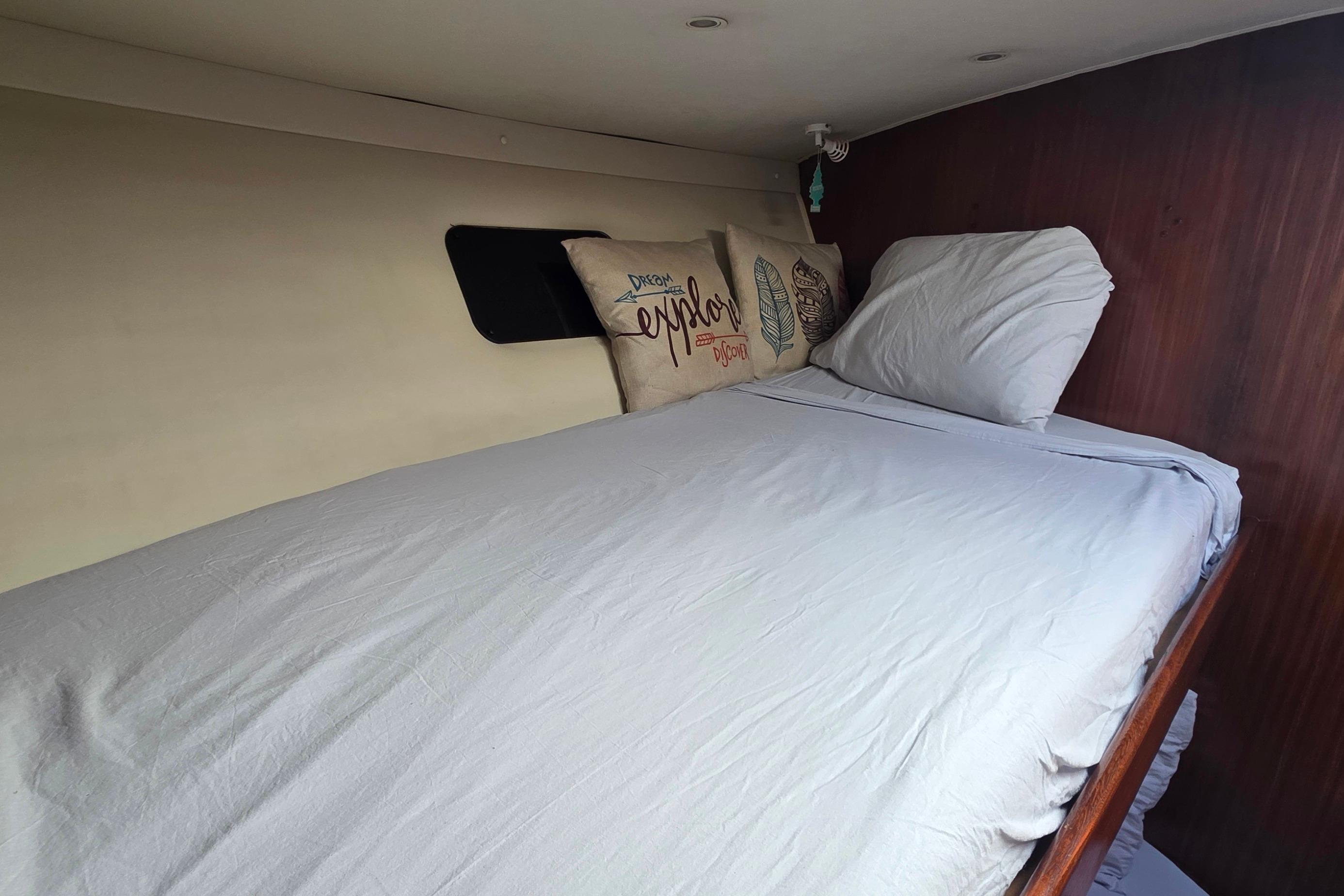 Cozy cabin bed inside 1989 Hatteras 52 Convertible yacht with decorative pillows.