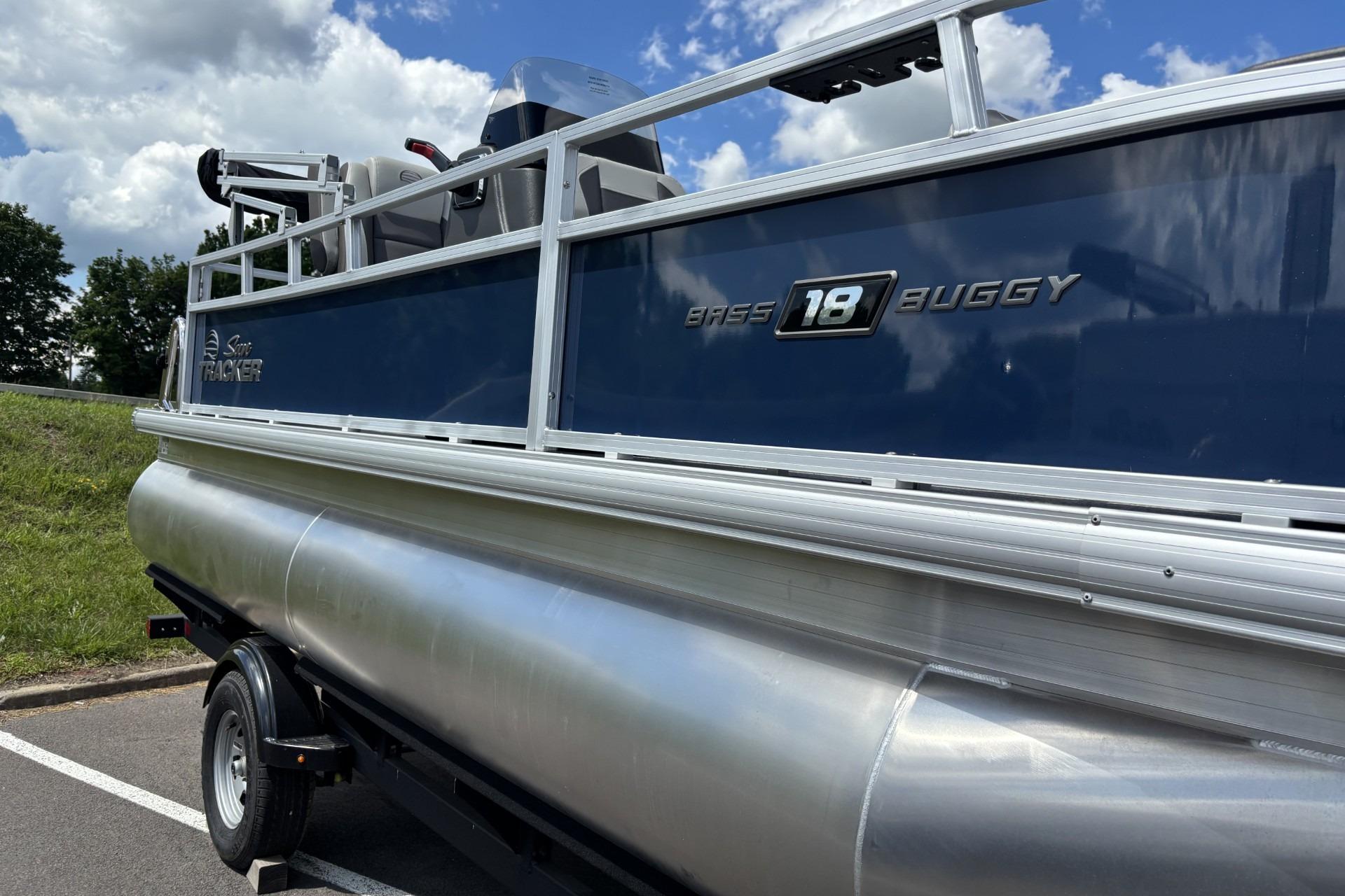 2026 Sun Tracker Bass Buggy 18 DLX pontoon boat on trailer under blue sky.