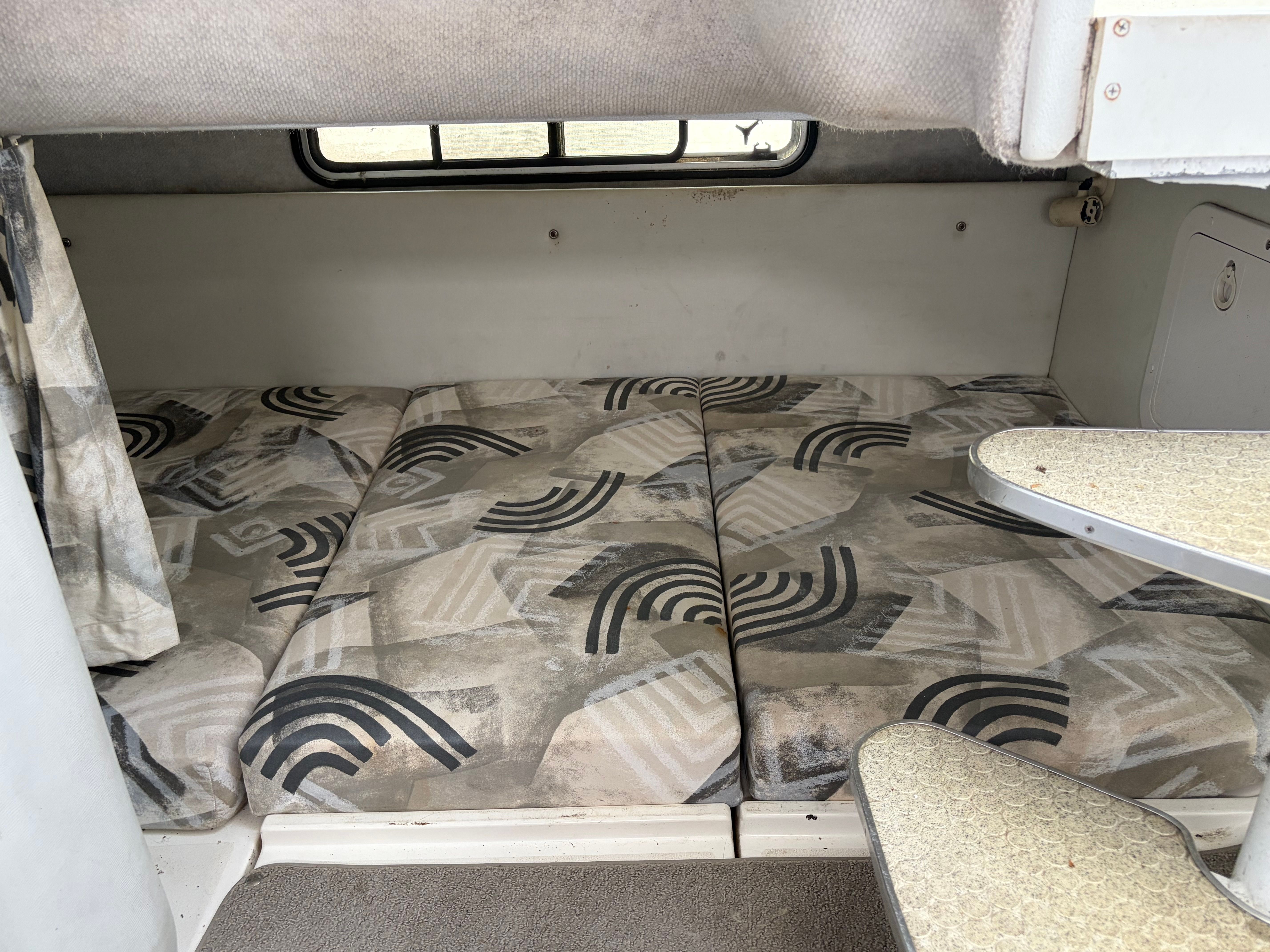 The cabin of the 2000 Wellcraft 290 Coastal features a cushioned sleeping area with patterned cushions.