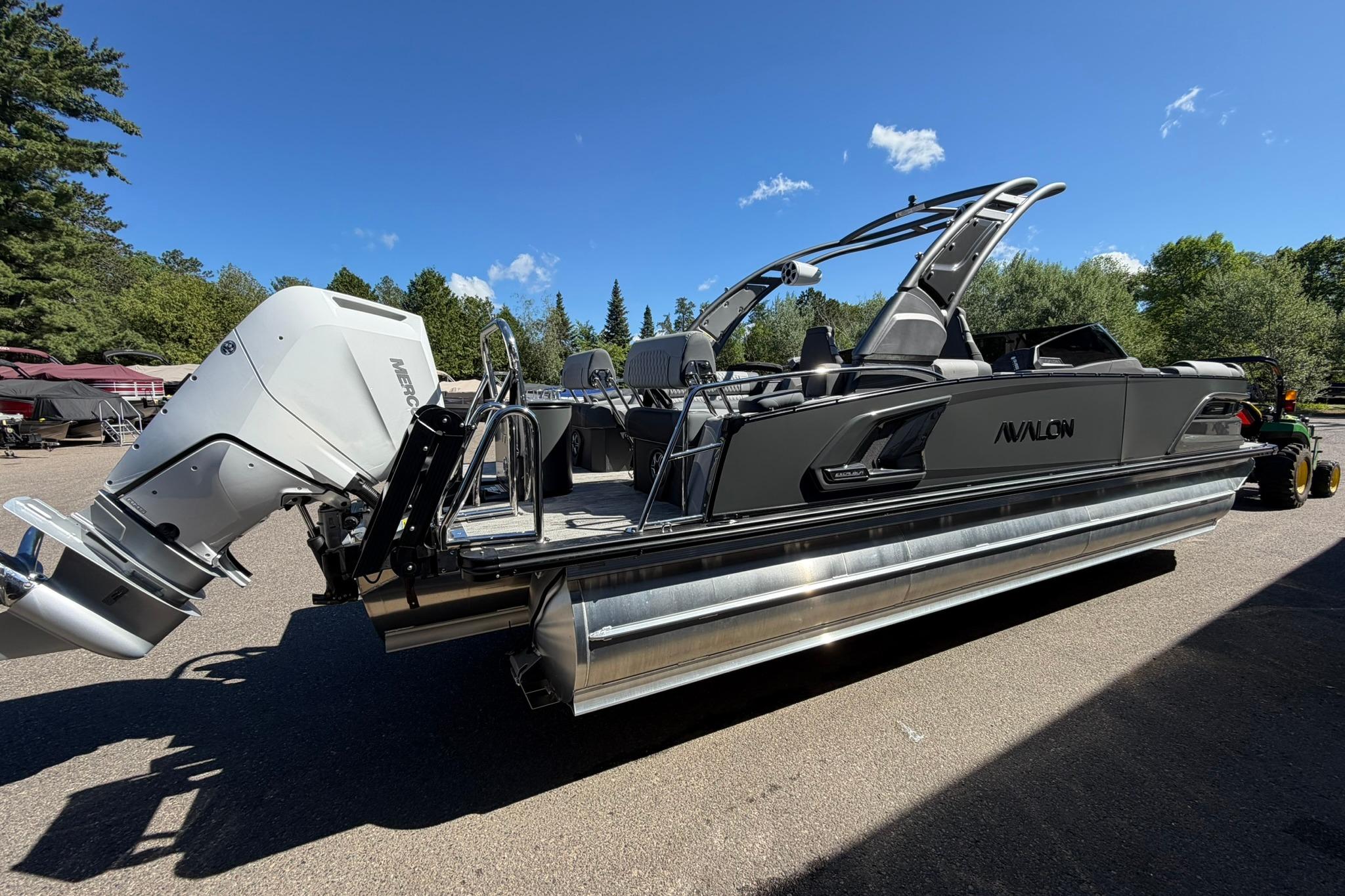 2026 Avalon Excalibur LTD Quad Lounge boat with windshield, parked outdoors under clear blue sky.