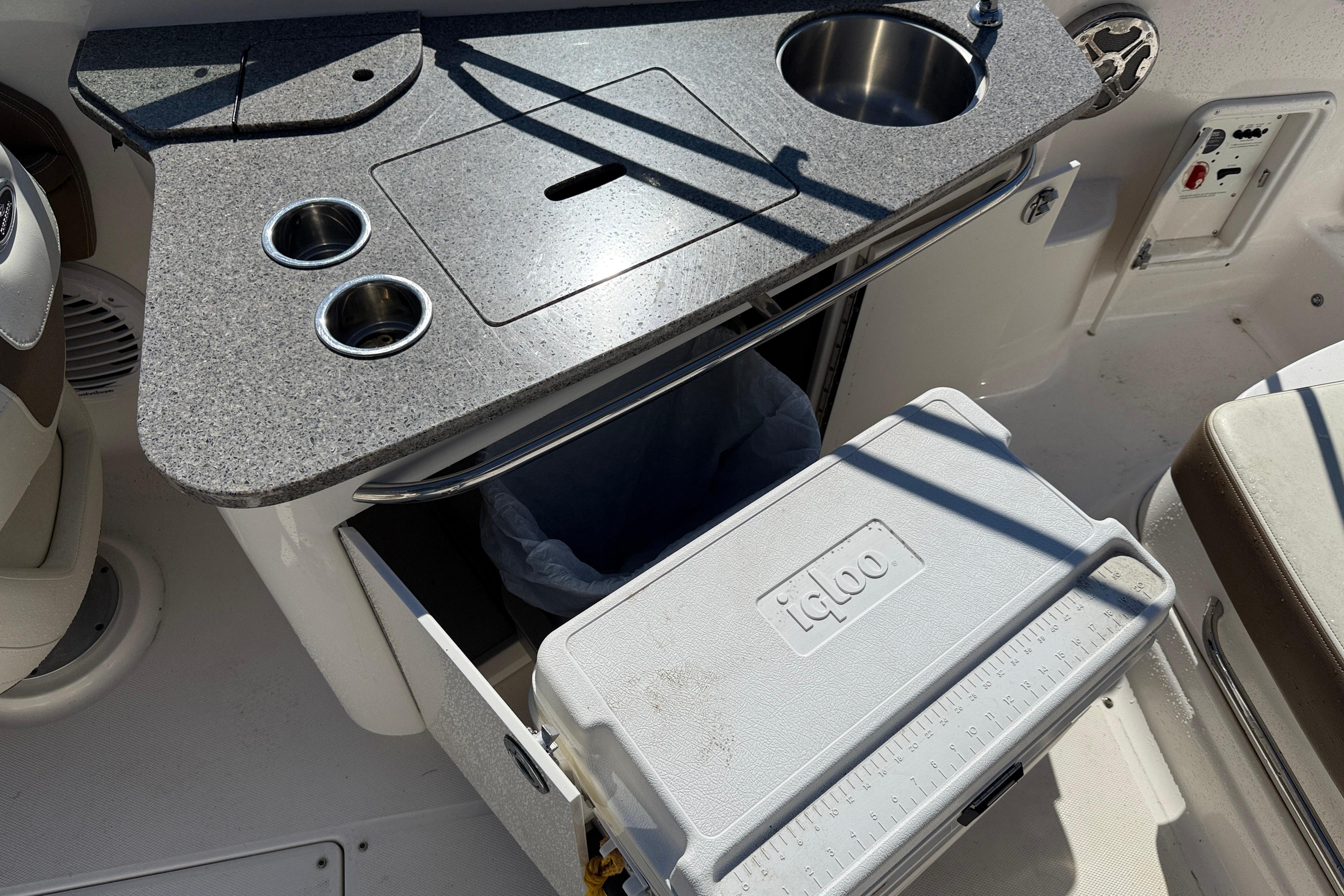 2014 Chaparral 264 Sunesta boat kitchenette with sink, countertop, and Igloo cooler.