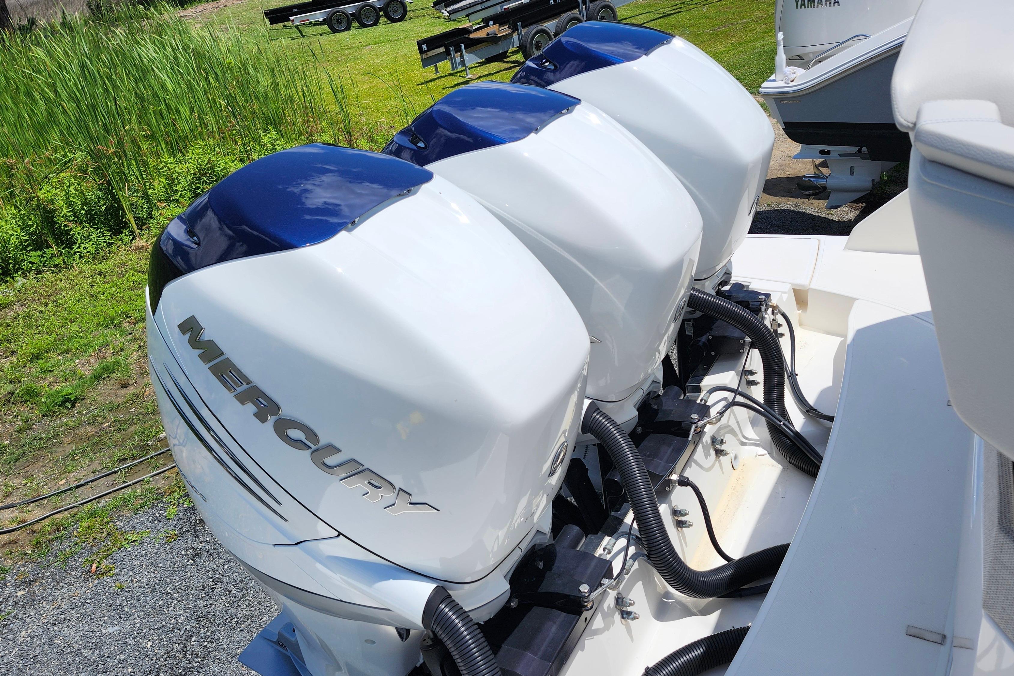 Triple Mercury outboard engines on a 2022 Tiara Yachts 38 LS, parked on a grassy area.