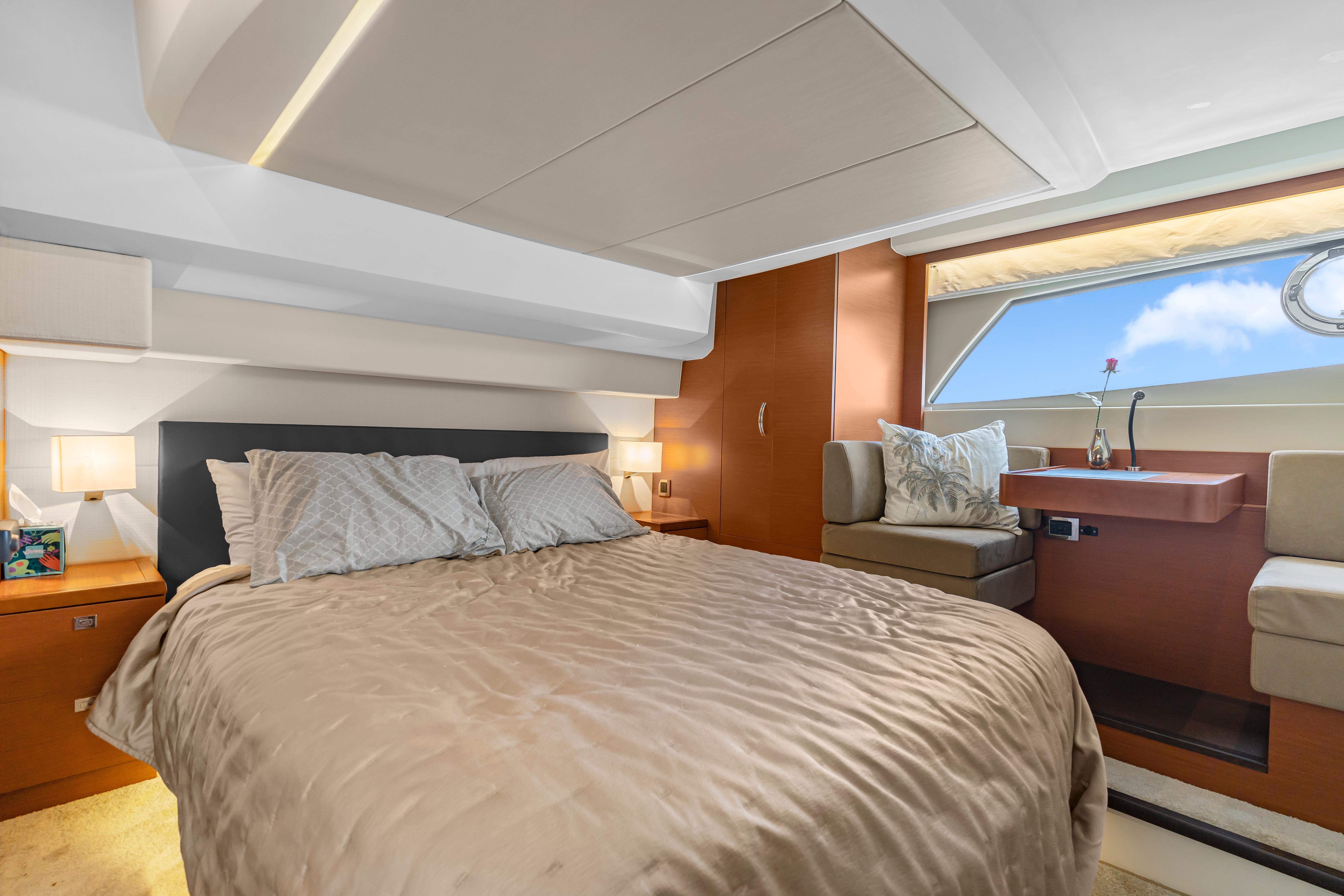 Luxurious bedroom interior of 2017 Prestige 500 yacht with elegant furnishings and large window view.
