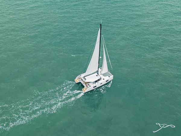 Aerial view of 2025 Nautitech 40 Open catamaran sailing on turquoise waters.