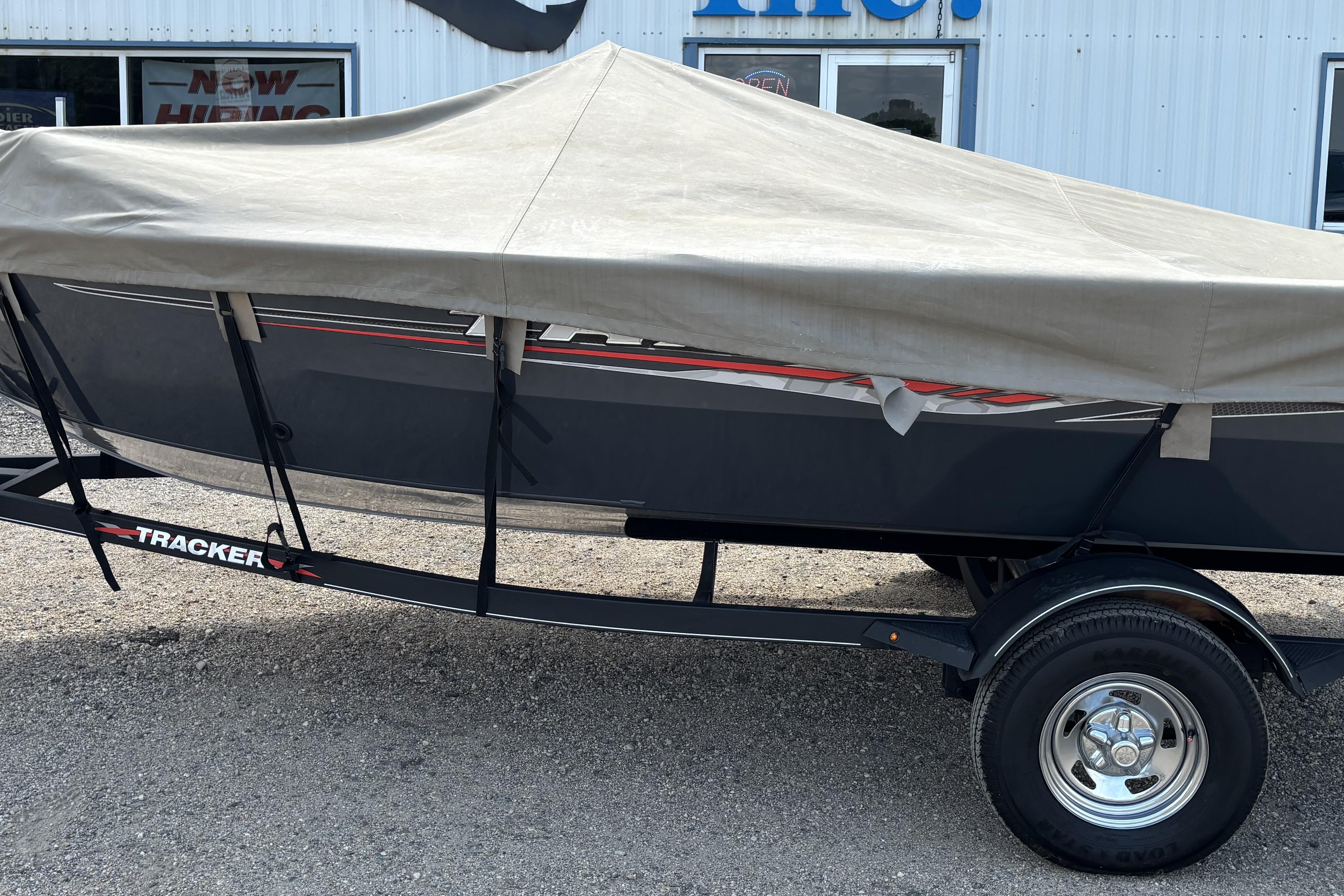 2021 Tracker Pro Guide V-16 WT boat covered on trailer, parked outside a building.