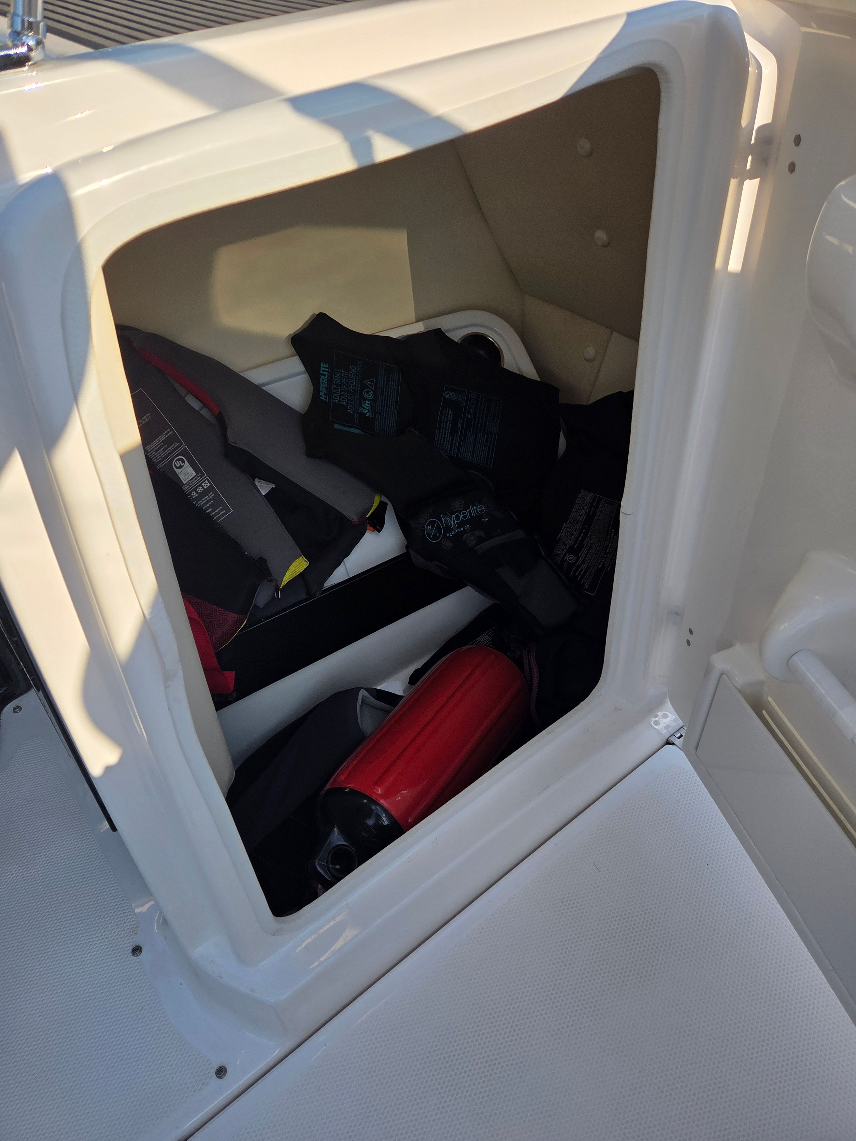 Boat storage compartment with life jackets and a fire extinguisher.