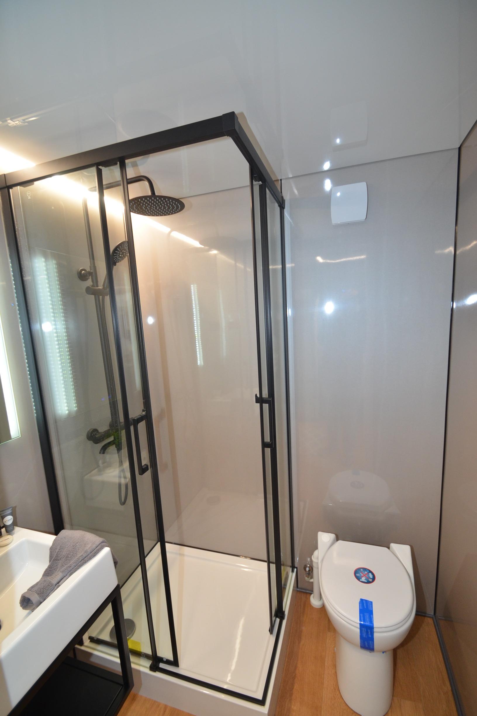 Modern bathroom with glass shower, toilet, and sink in La Mare Modern 11, 2024 model.