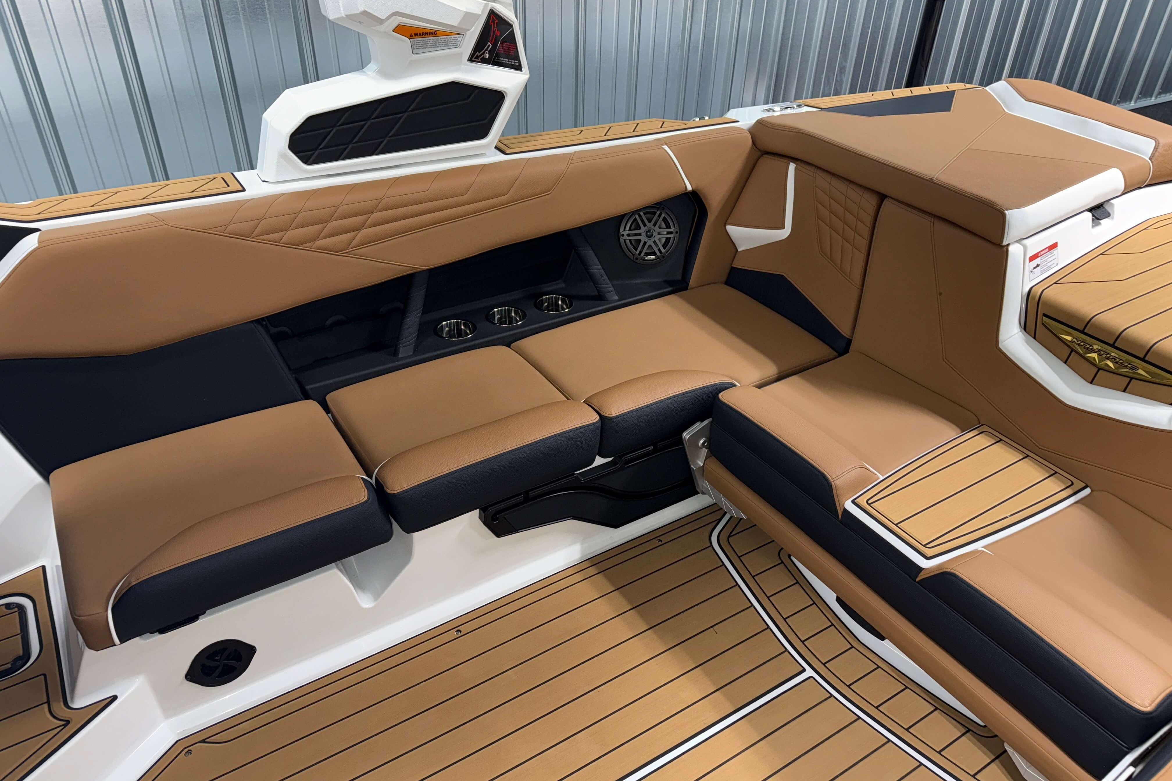 2026 Nautique Super Air Nautique S23 interior with tan and black seating, cup holders, and speaker.