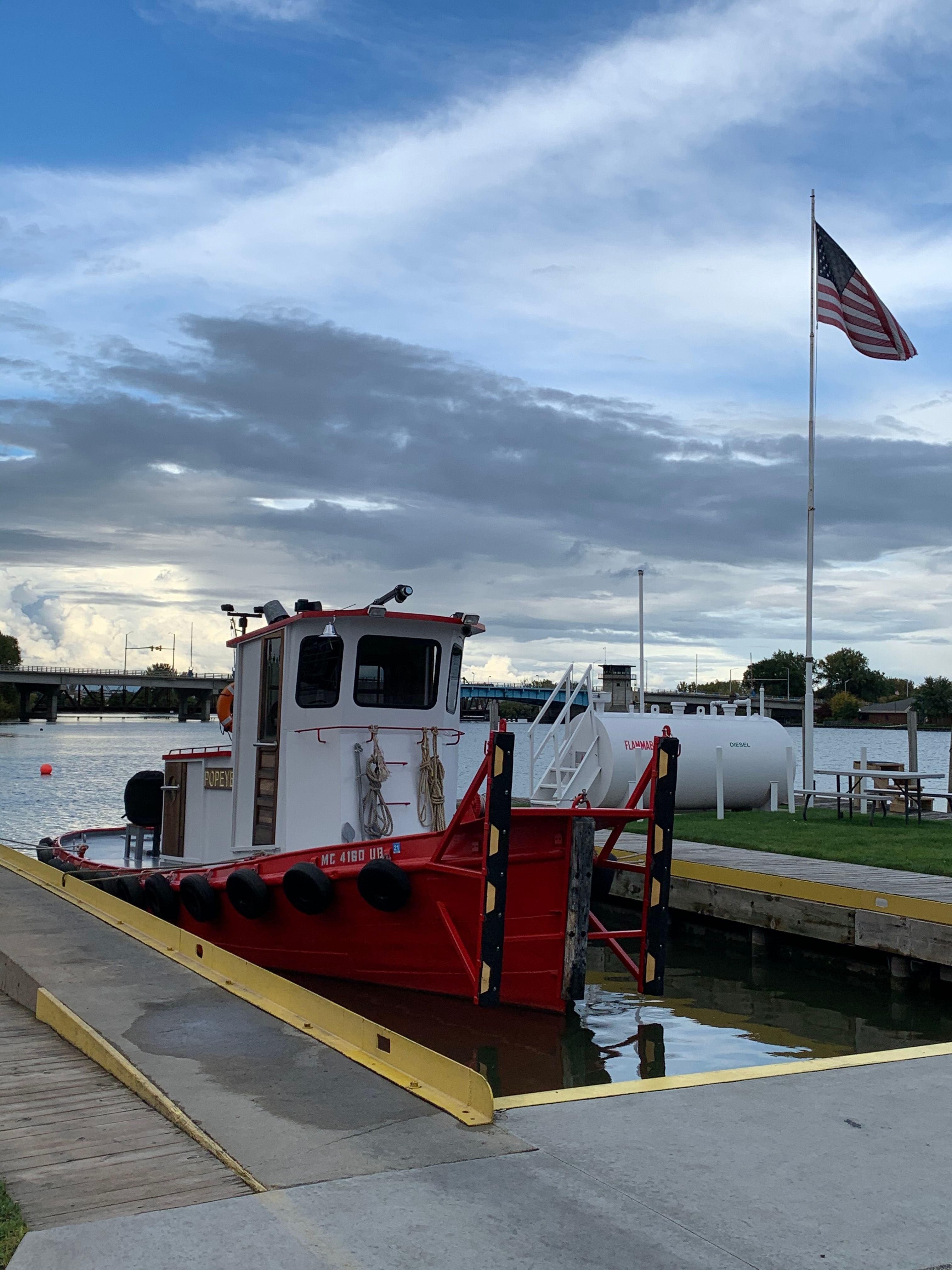 1953 Harbor Tugboat docked with American flag in the background.