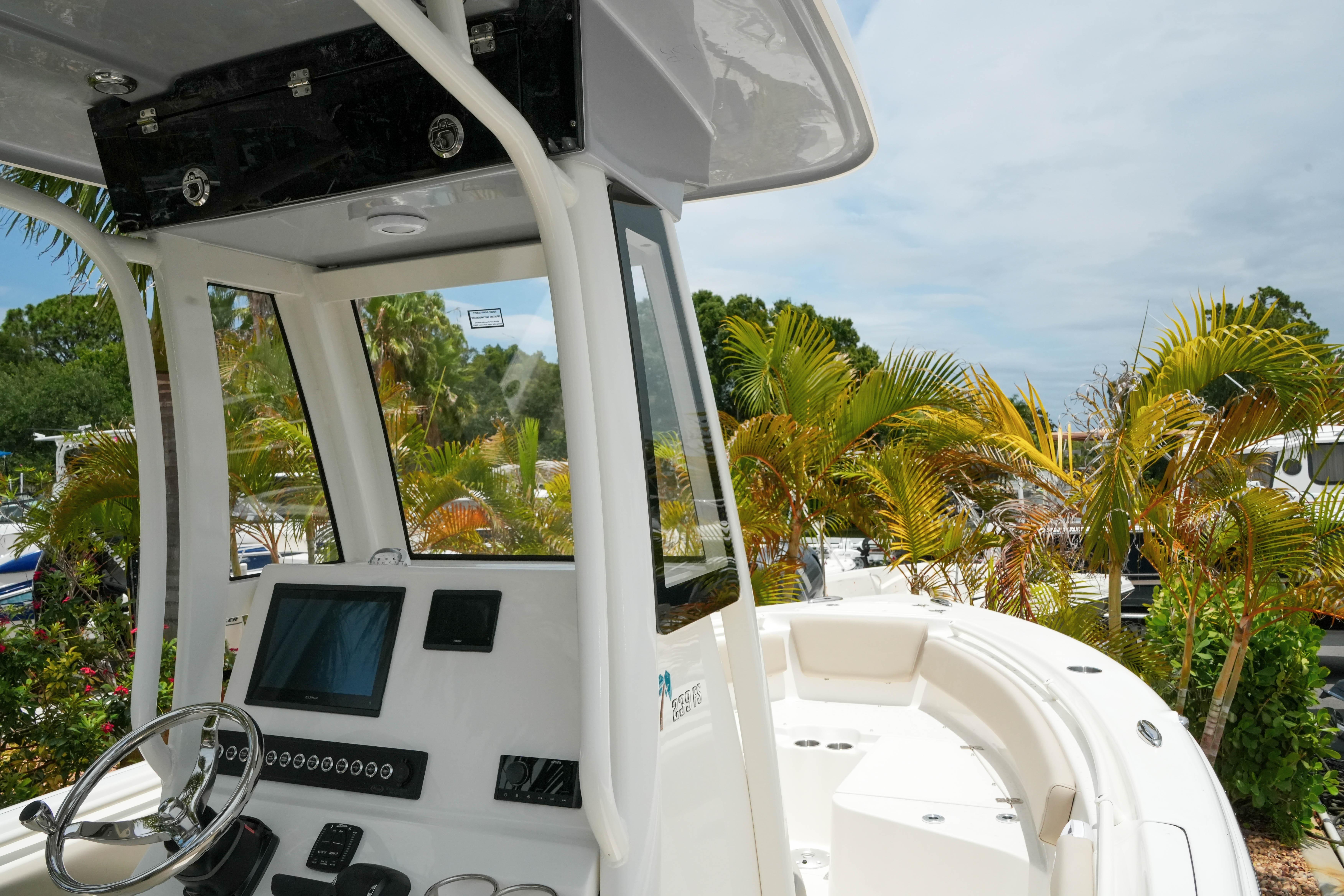 2026 Key West 239 FS boat interior with steering console, surrounded by lush greenery.