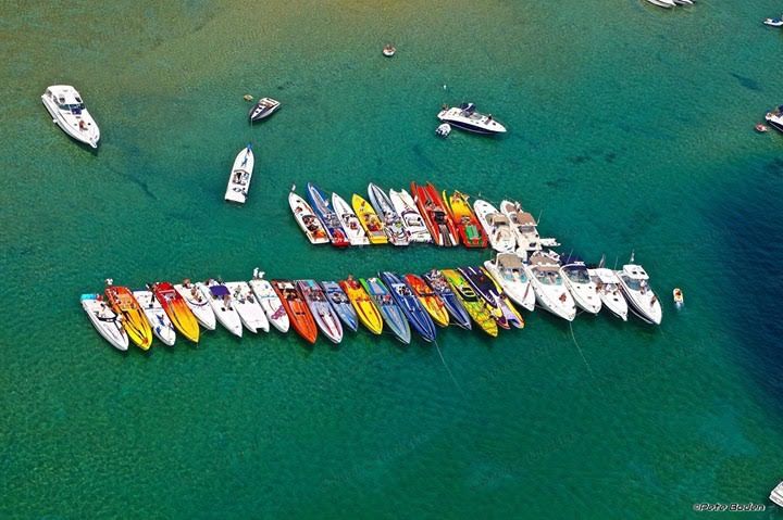 Colorful boats, including a 2001 Fountain Lightning, on clear water.