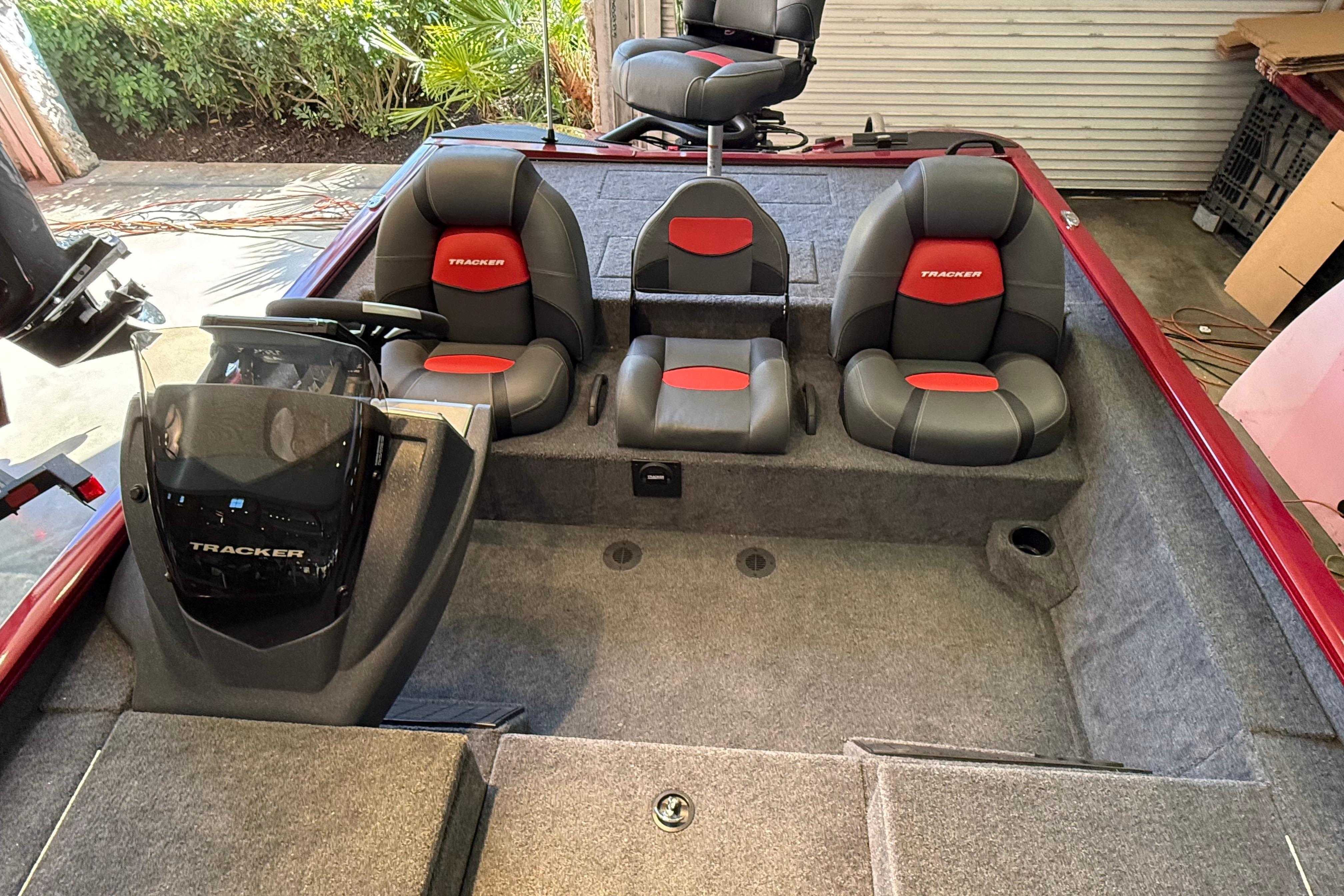 2025 Tracker Savage 215 boat interior with gray and red seating, steering console, and carpeted flooring.