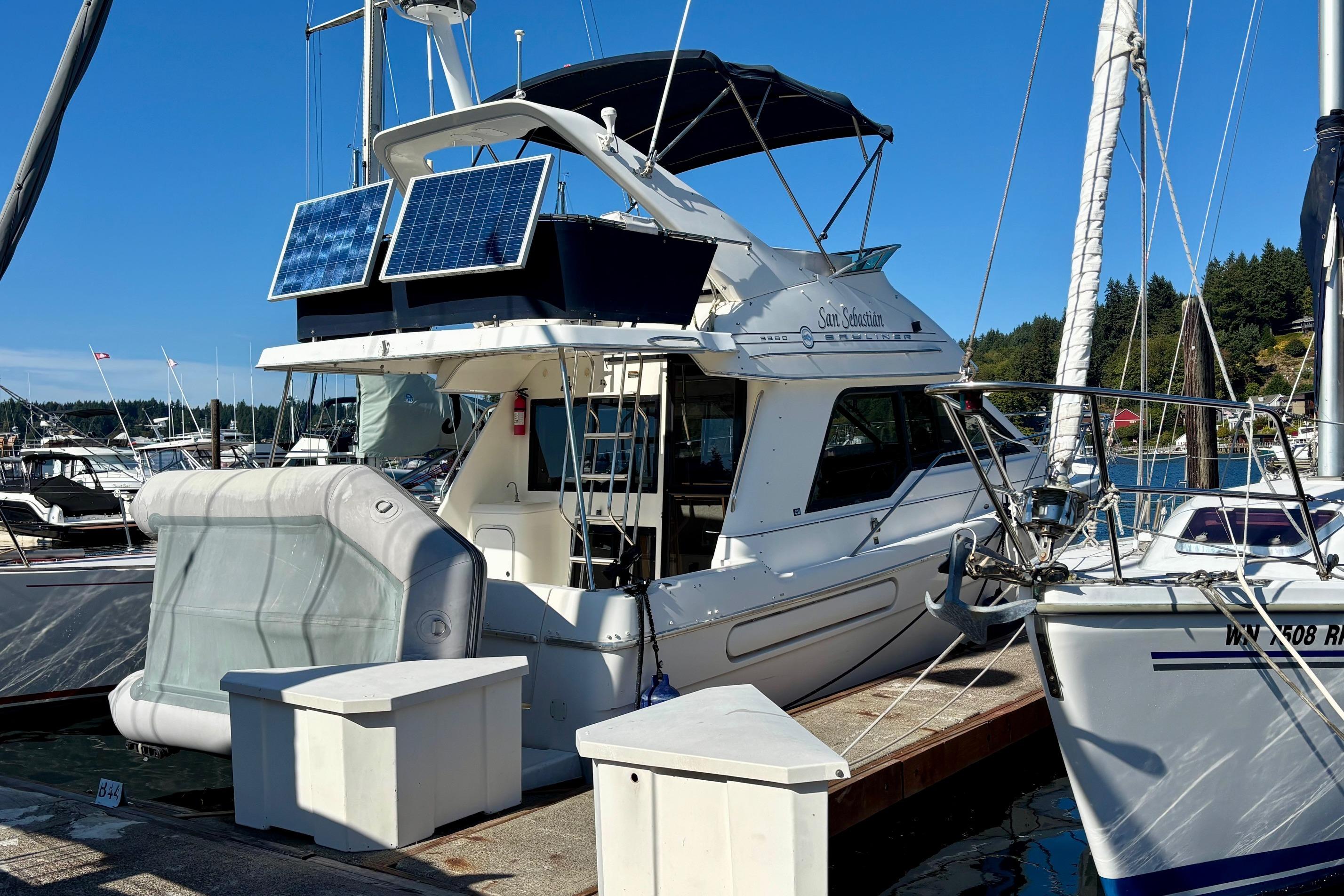 1998 Bayliner 3388 Command Bridge Motoryacht docked with solar panels, sunny marina setting.