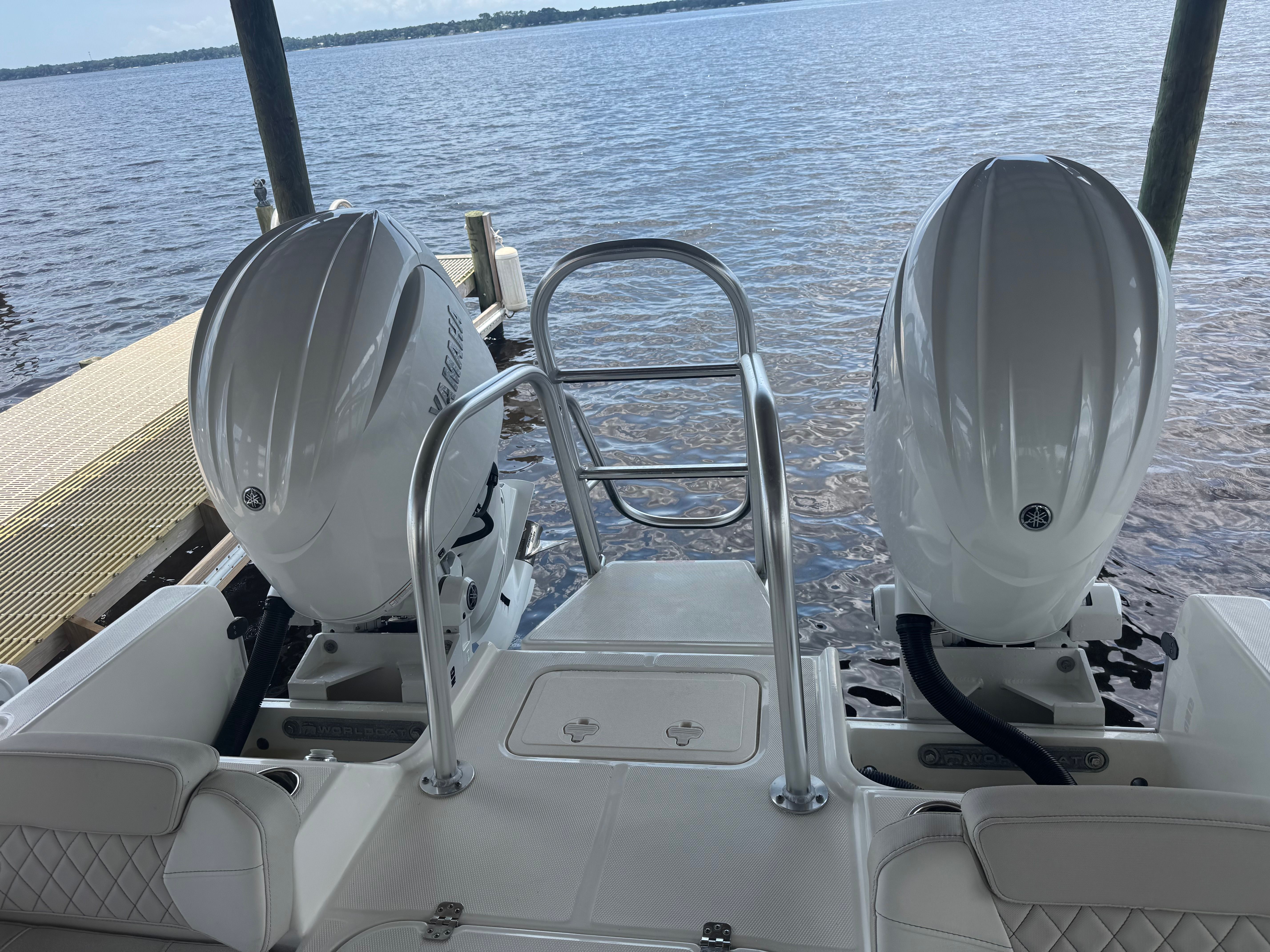 Two outboard motors on a boat by the water.