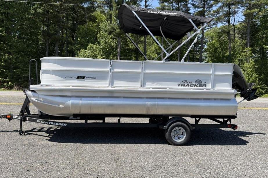 2026 Sun Tracker Party Barge 18 DLX pontoon boat on trailer, parked outdoors.