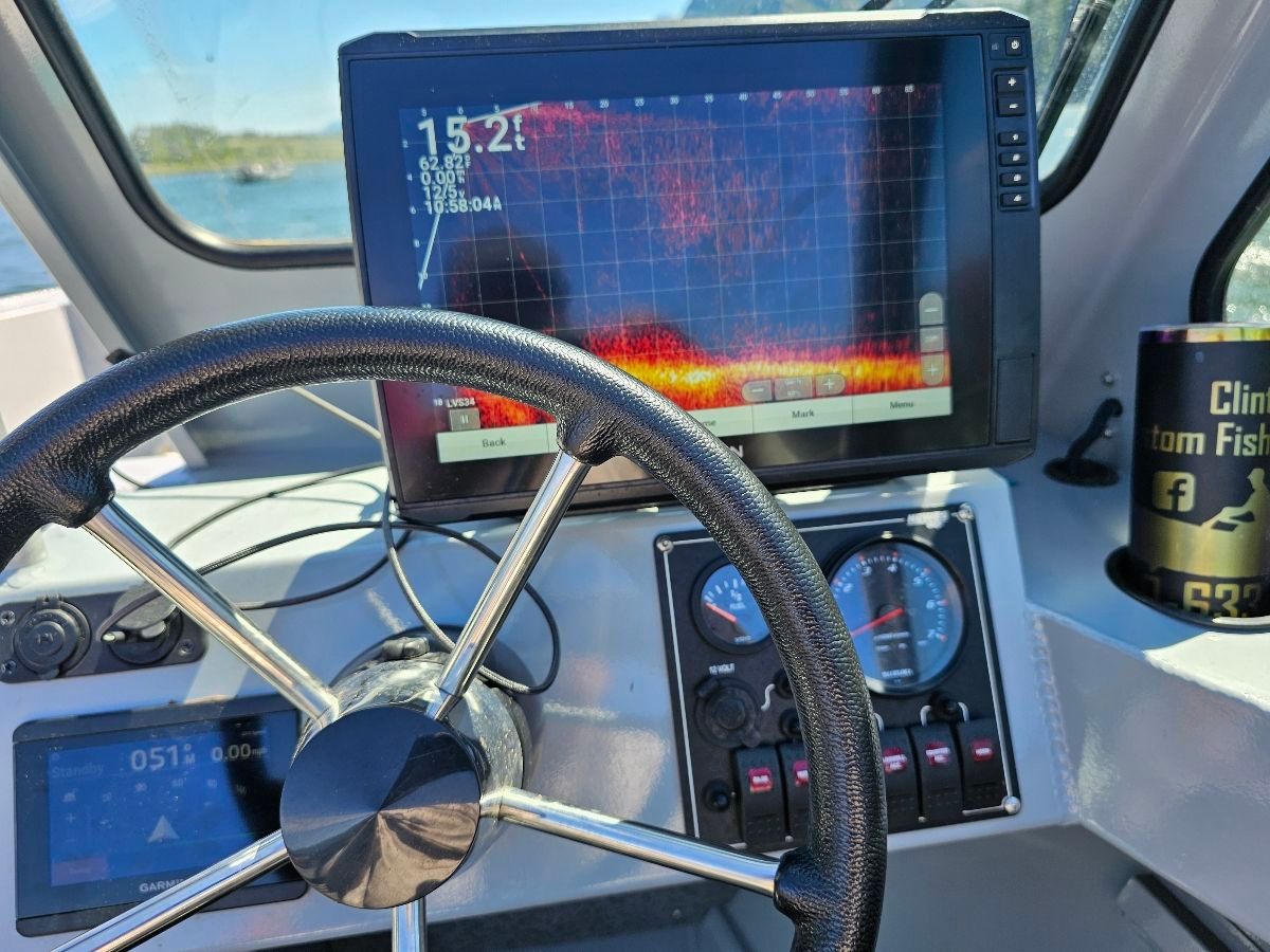 The image shows a boat's helm with a large screen and instruments.
