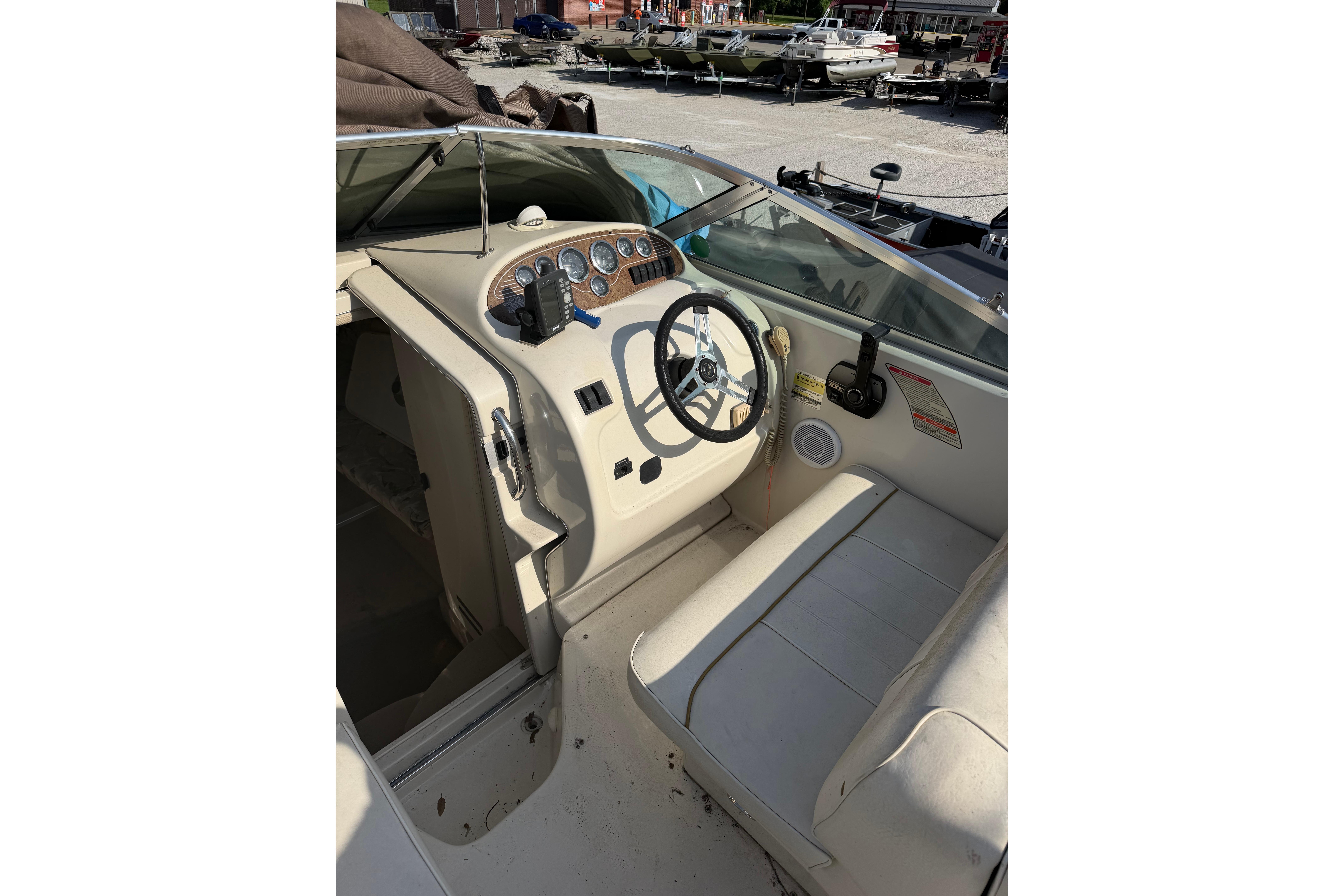 1999 Sea Ray 240 Sundancer boat cockpit with steering wheel and control panel.