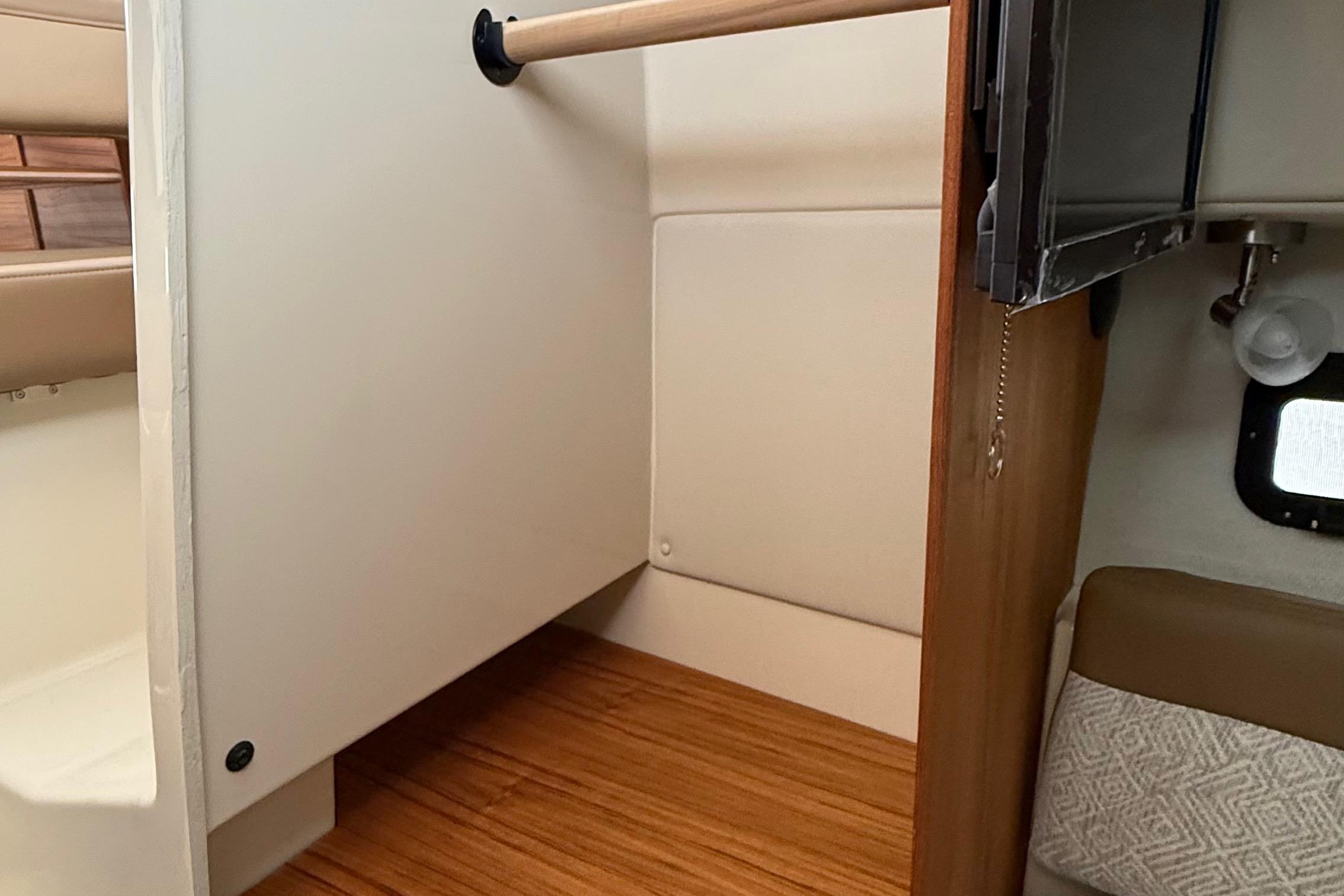 Interior of 2025 Ranger Tugs R-25, featuring a compact storage area and wooden flooring.
