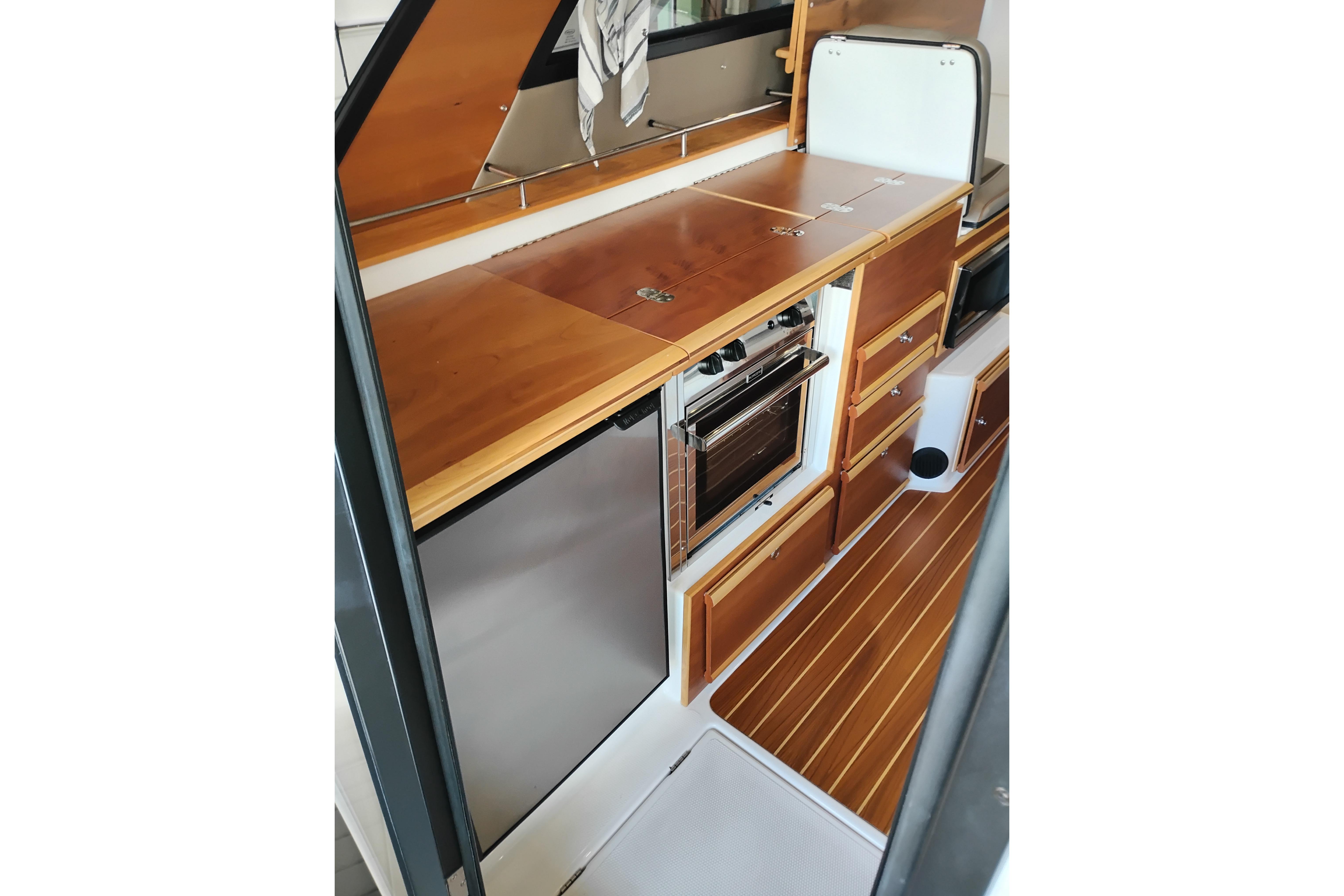 2022 Cutwater C-32 Coupe kitchen with wood cabinetry and stainless steel appliances.