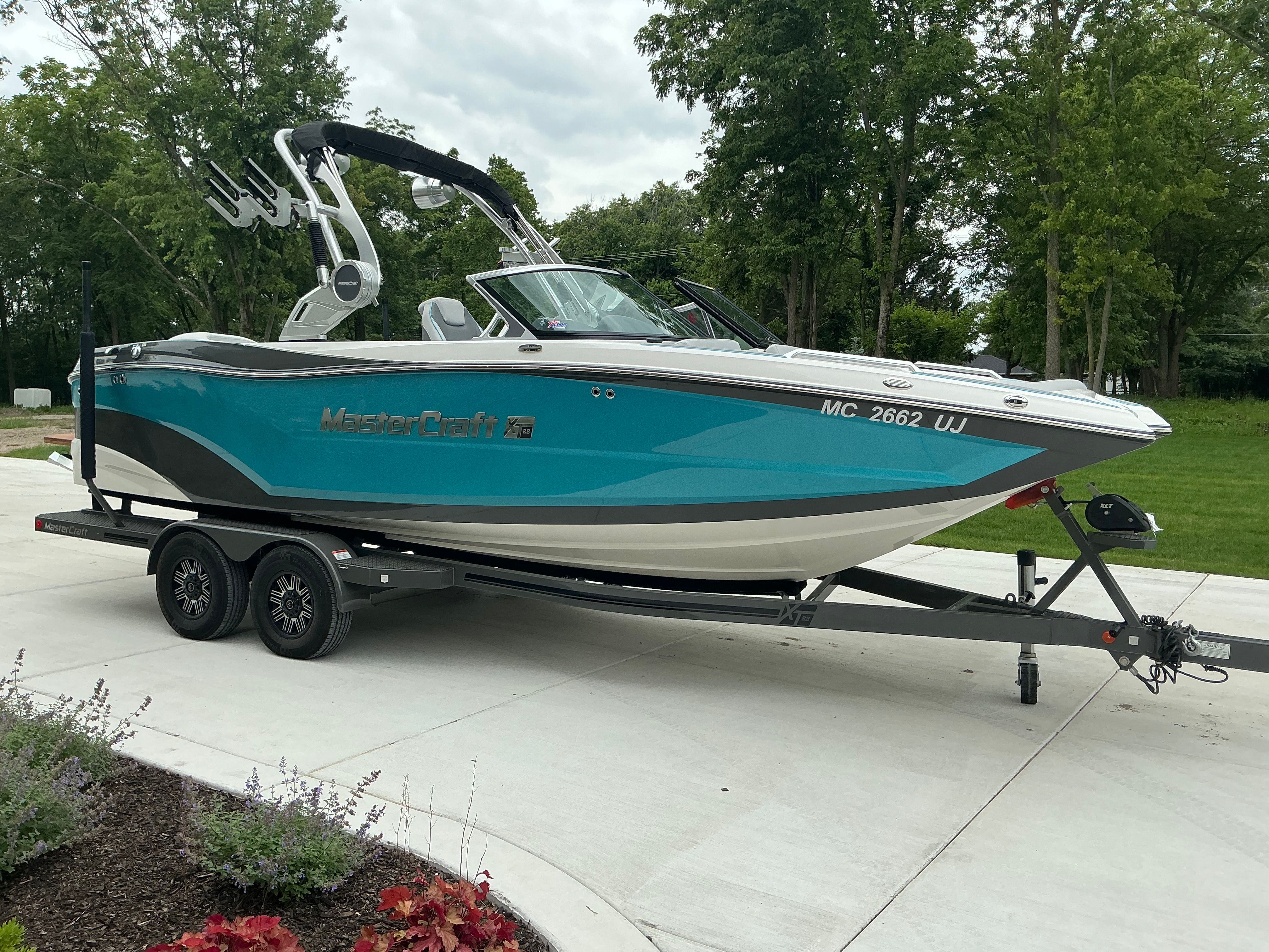 A turquoise 2019 MasterCraft XT22 sits on a trailer in a driveway.