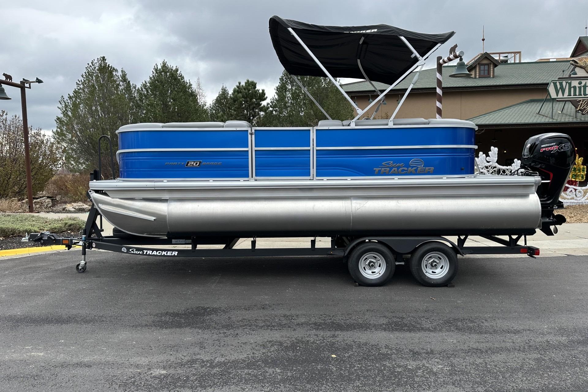 2026 Sun Tracker Party Barge 20 DLX pontoon boat on trailer, parked outdoors.