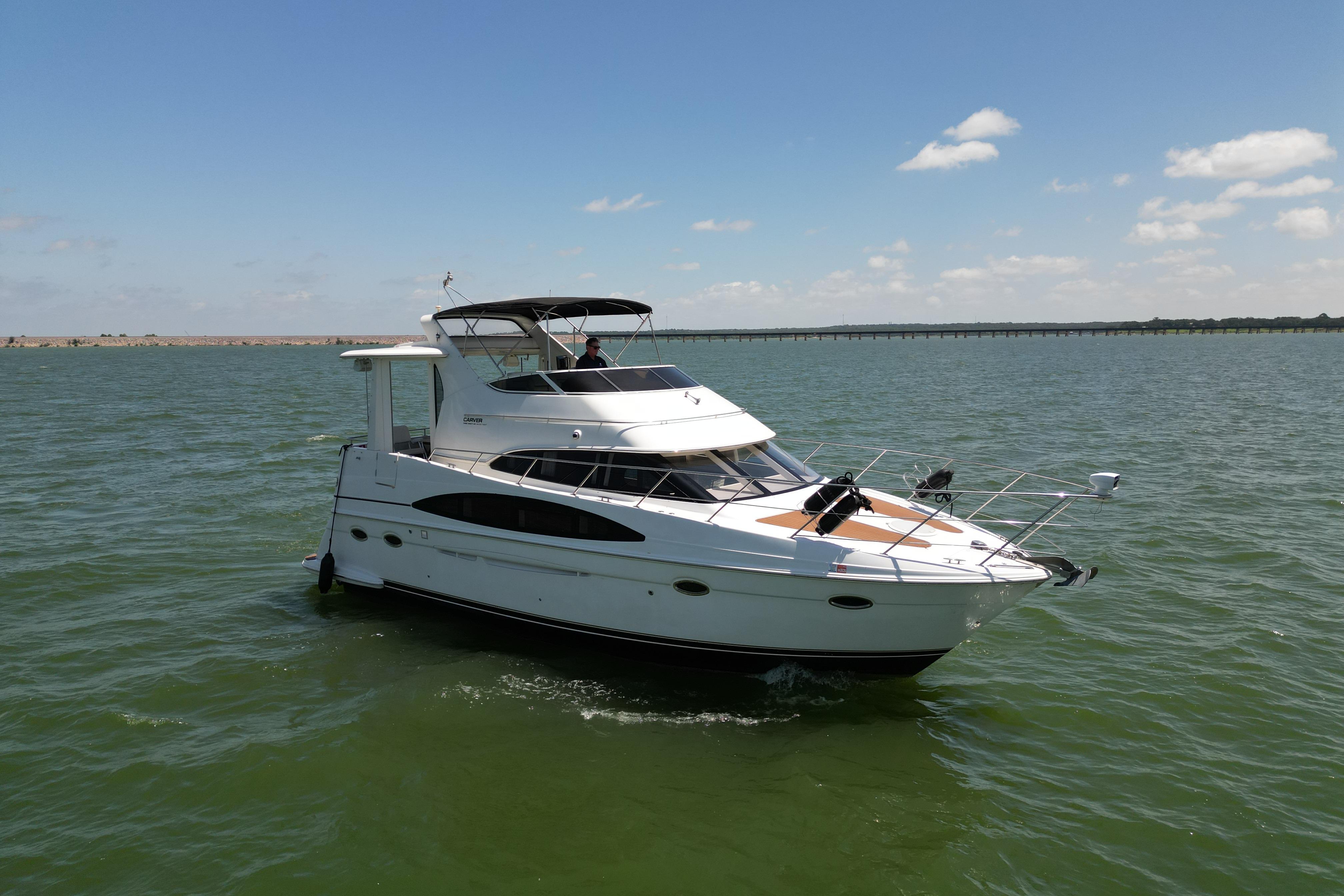 2002 Carver 396 Motor Yacht cruising on open water under a clear blue sky.