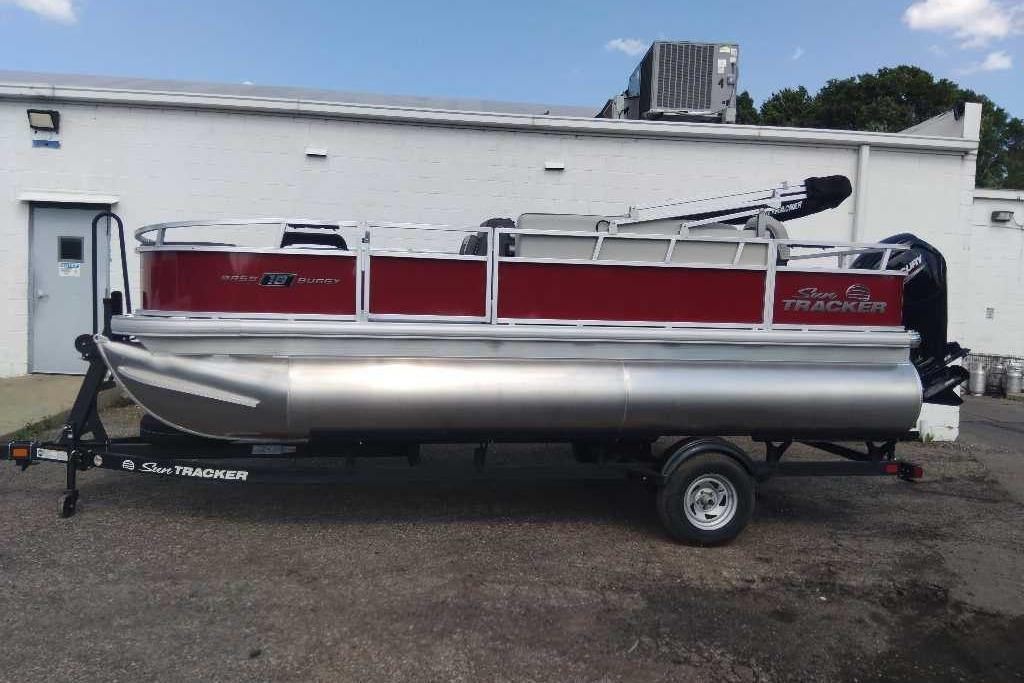 2026 Sun Tracker Bass Buggy 18 DLX pontoon boat on trailer, parked outdoors.