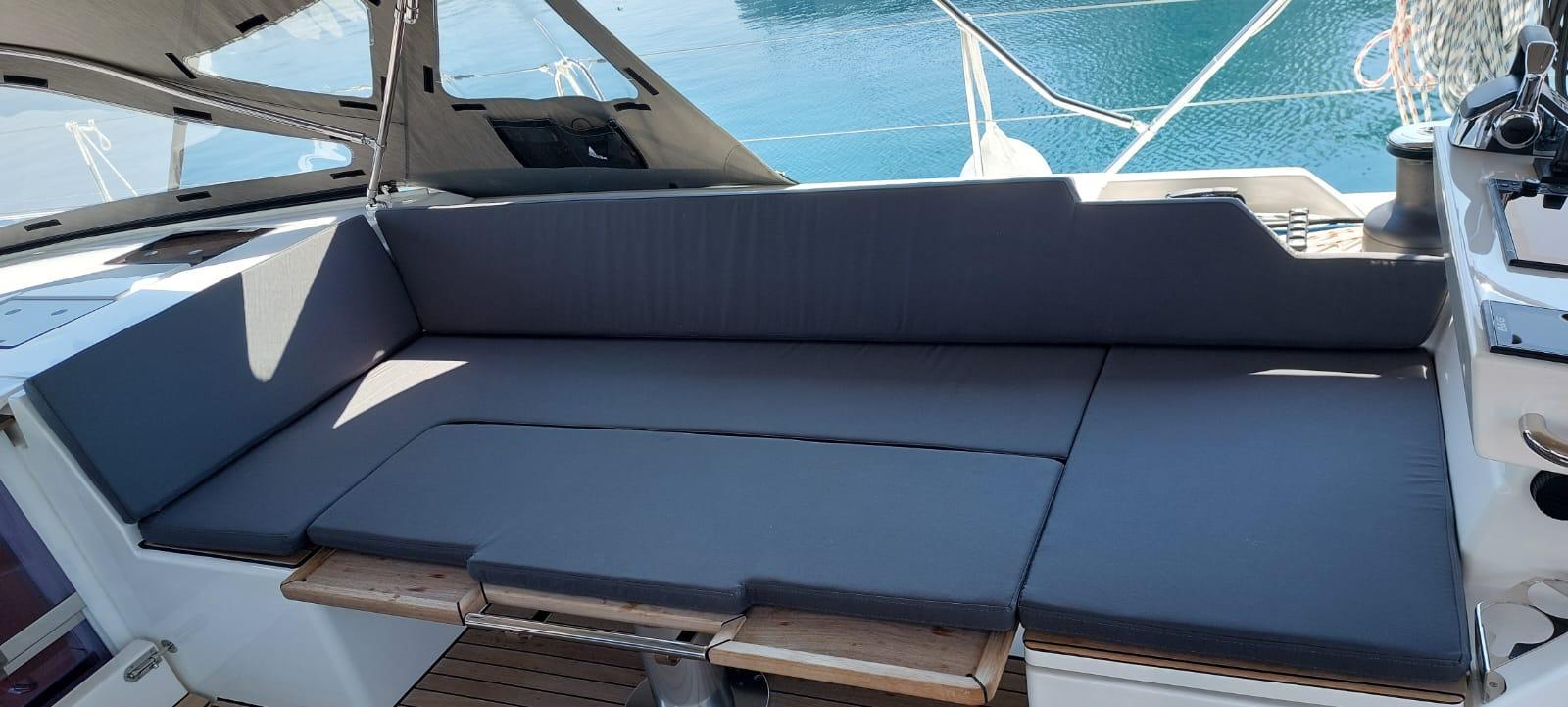 Luxurious seating area on a 2023 Bavaria C57 yacht, featuring sleek gray cushions.