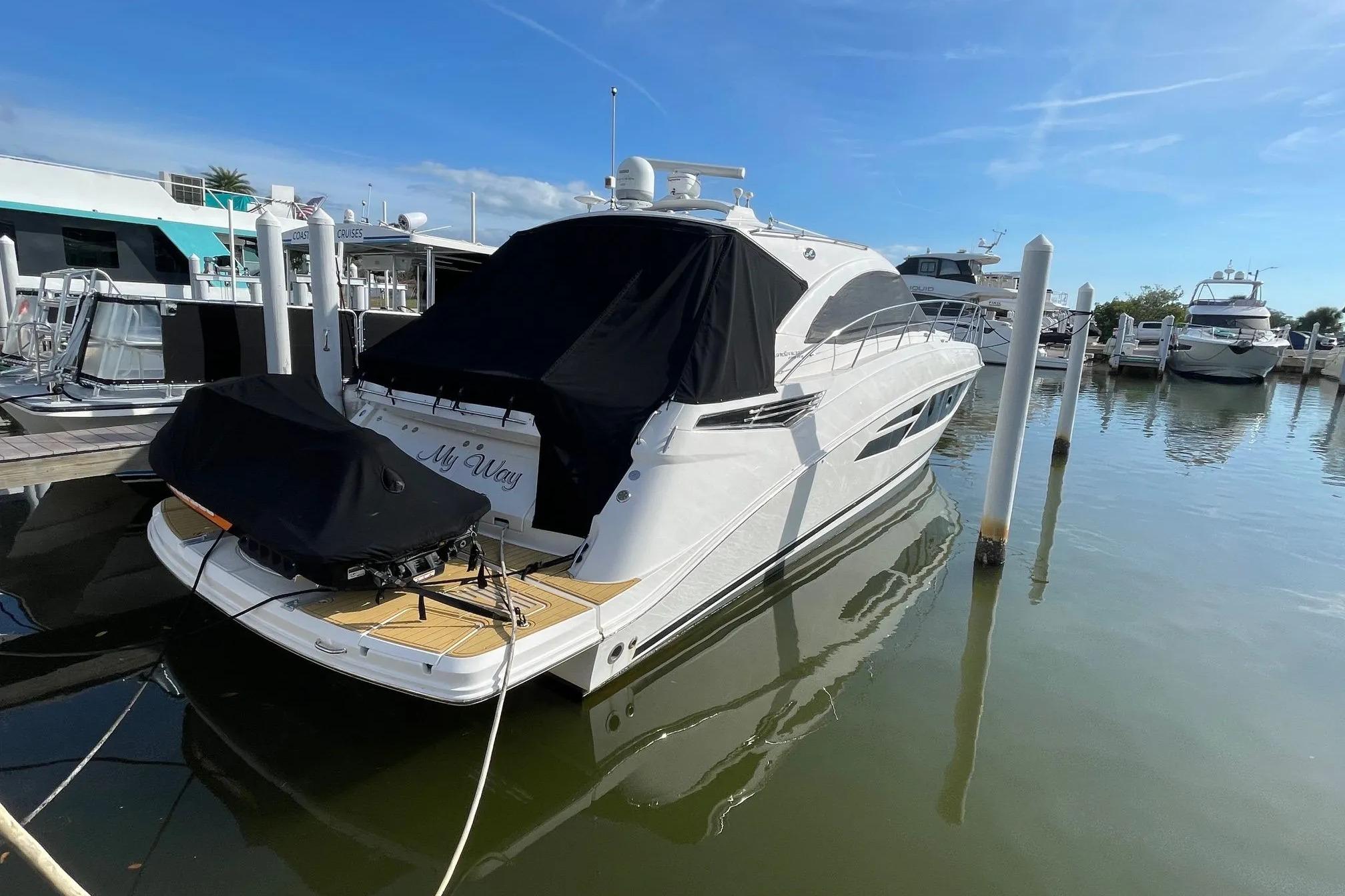 2016 Sea Ray Sundancer 510 yacht docked at marina, covered and reflecting on water.
