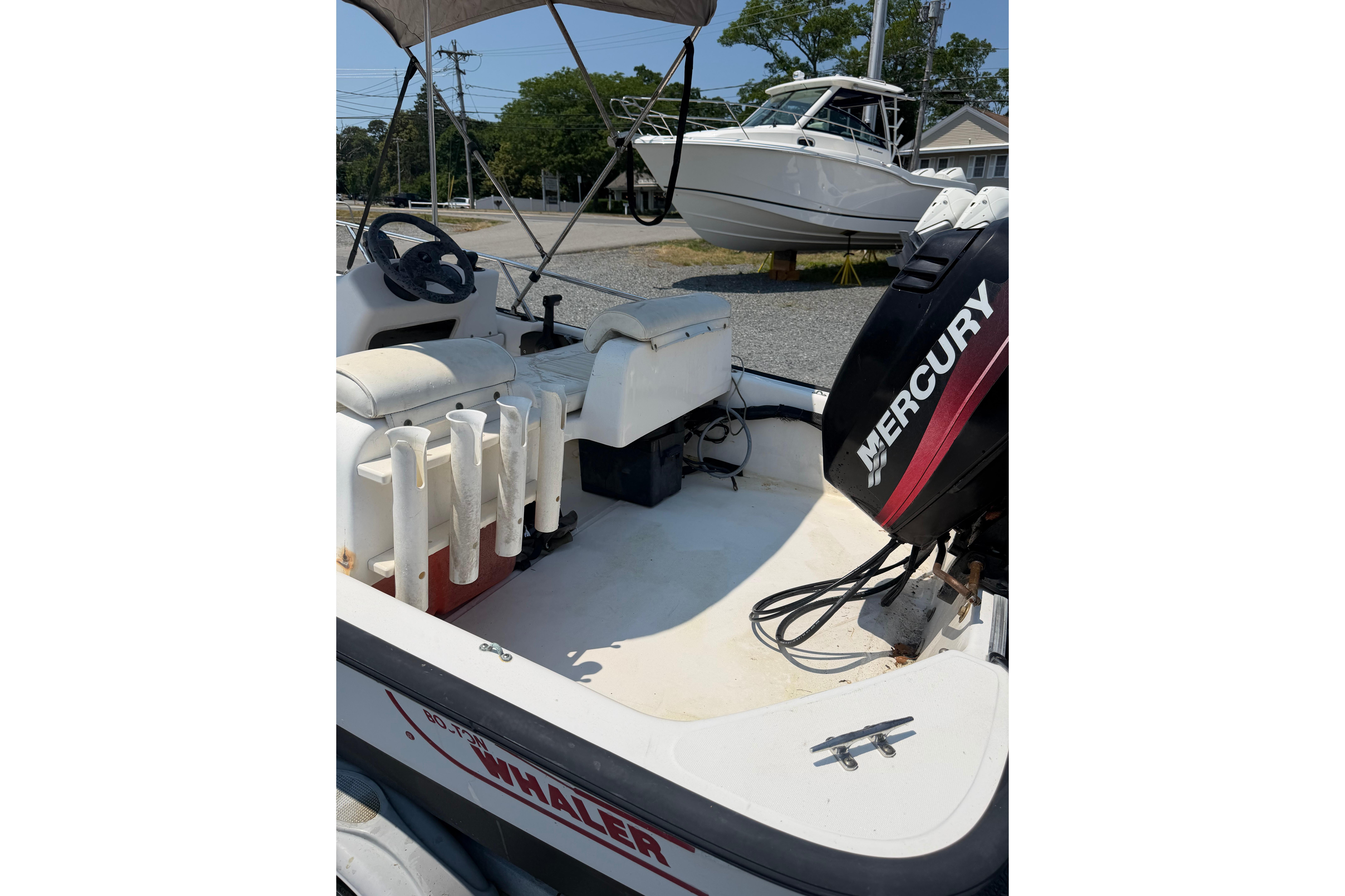 2003 Boston Whaler 130 Super Sport boat with Mercury engine, featuring seating and rod holders.
