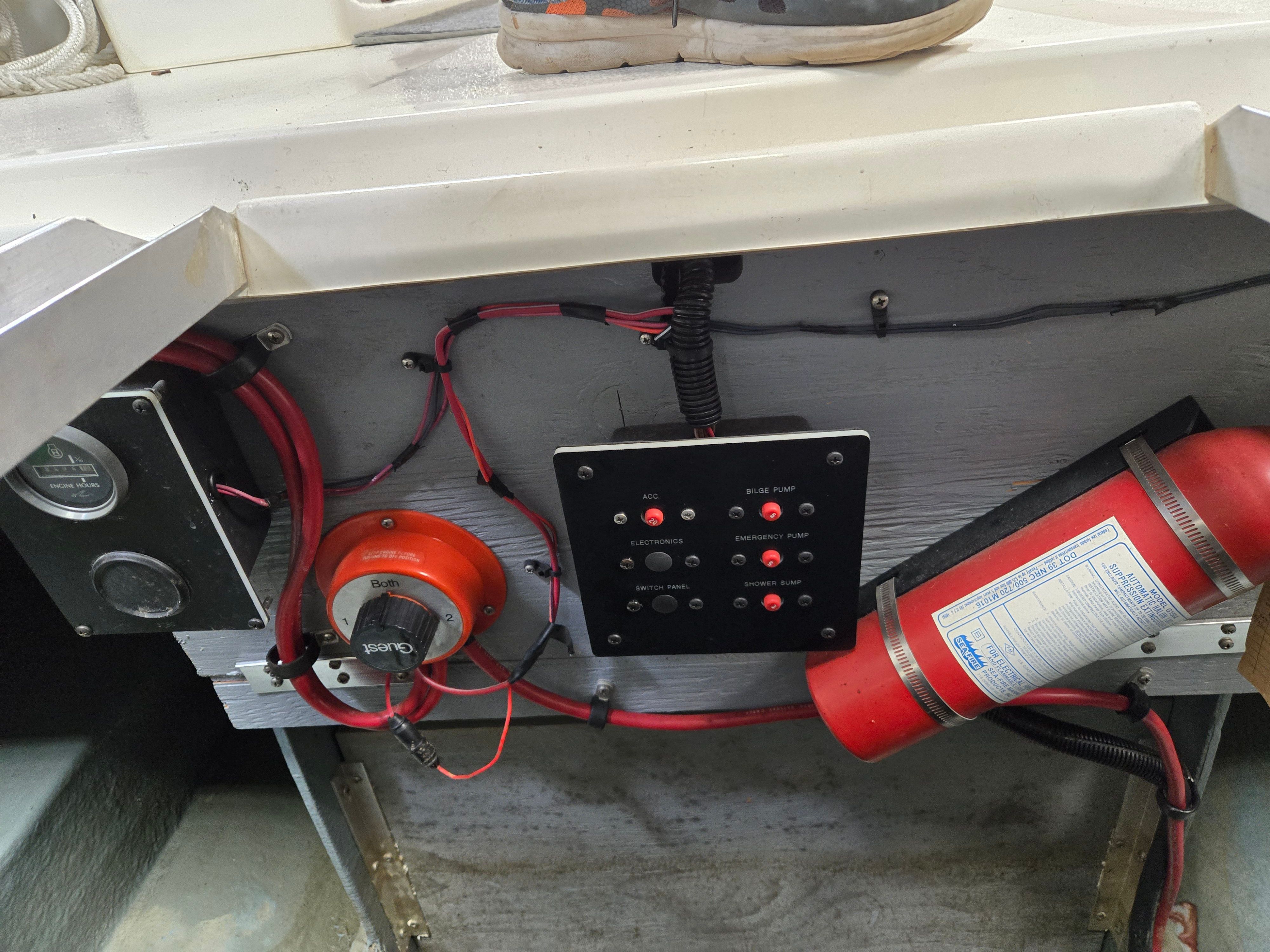 A control panel with switches and a fire extinguisher on a boat.