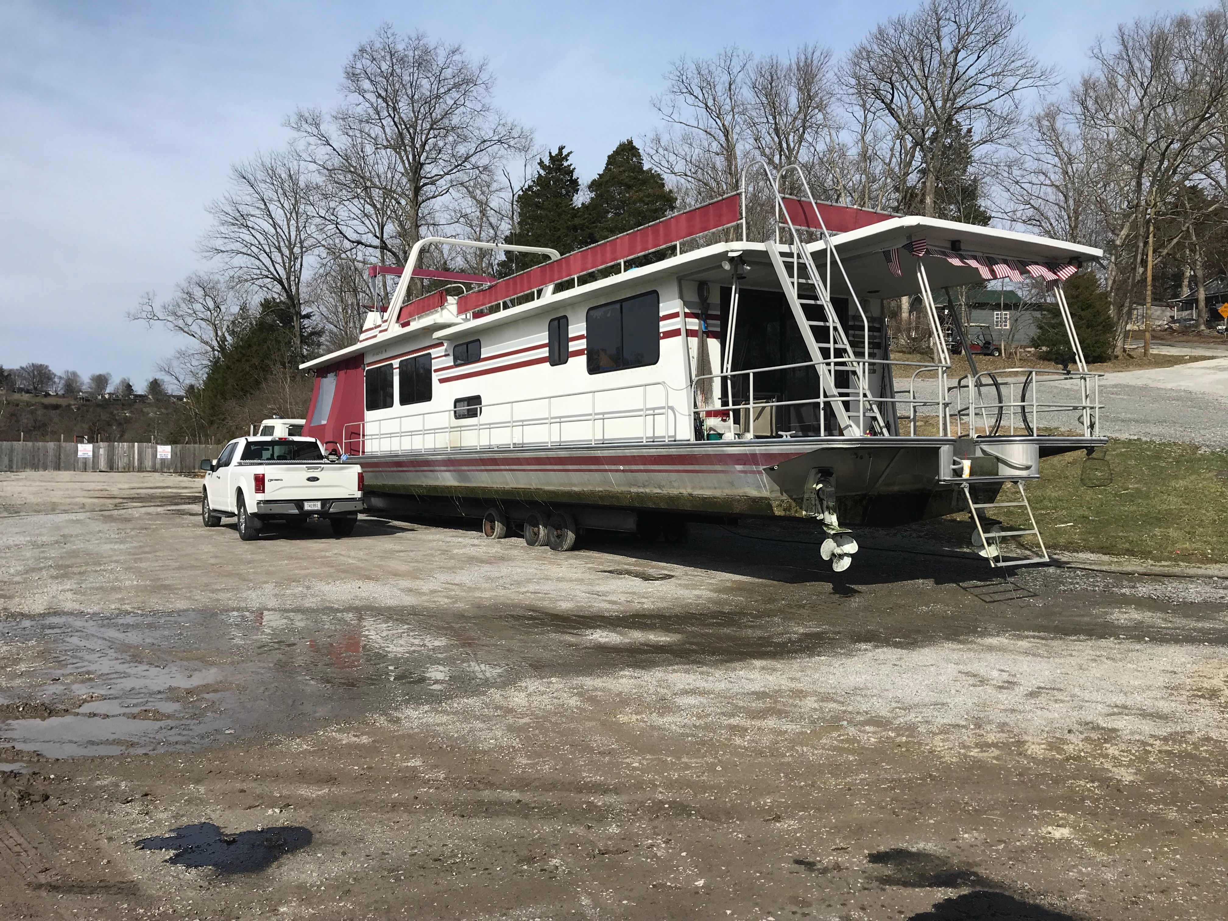 A 1989 Sumerset houseboat on a trailer, towed by a white truck.