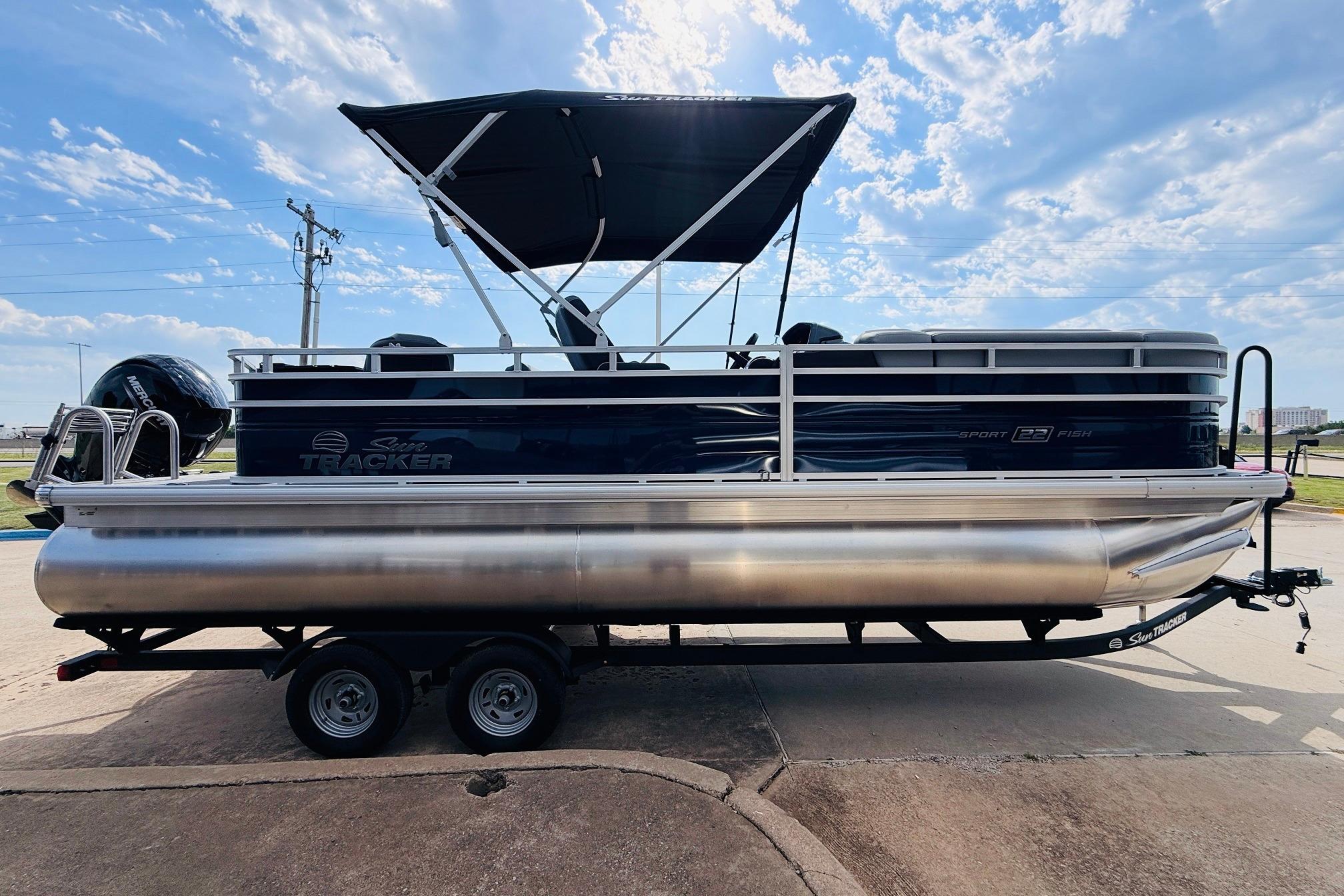 2026 Sun Tracker SportFish 22 DLX pontoon boat on trailer under a sunny sky.