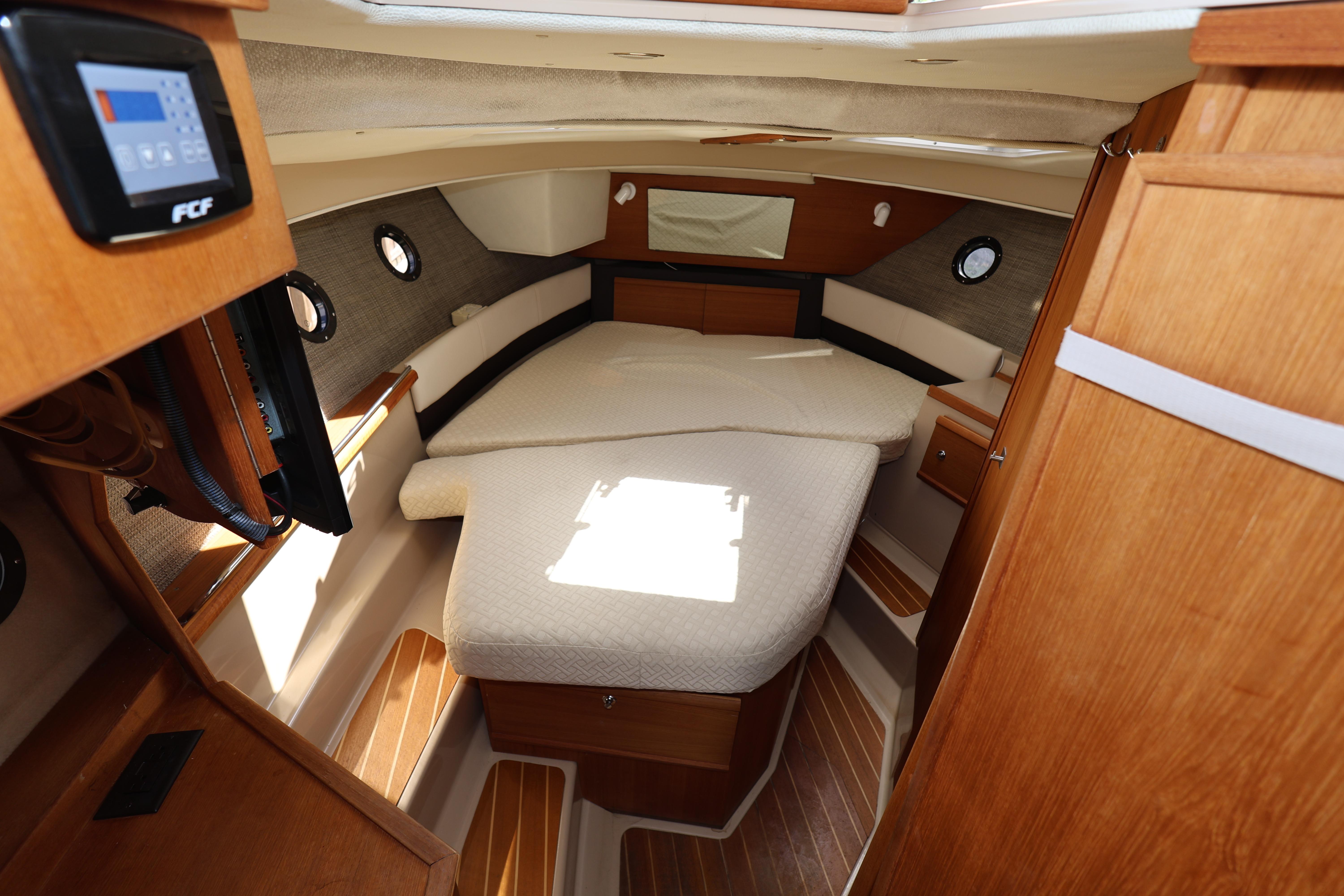 2015 Ranger Tugs R-29 S cabin interior with cozy bed and wooden accents.