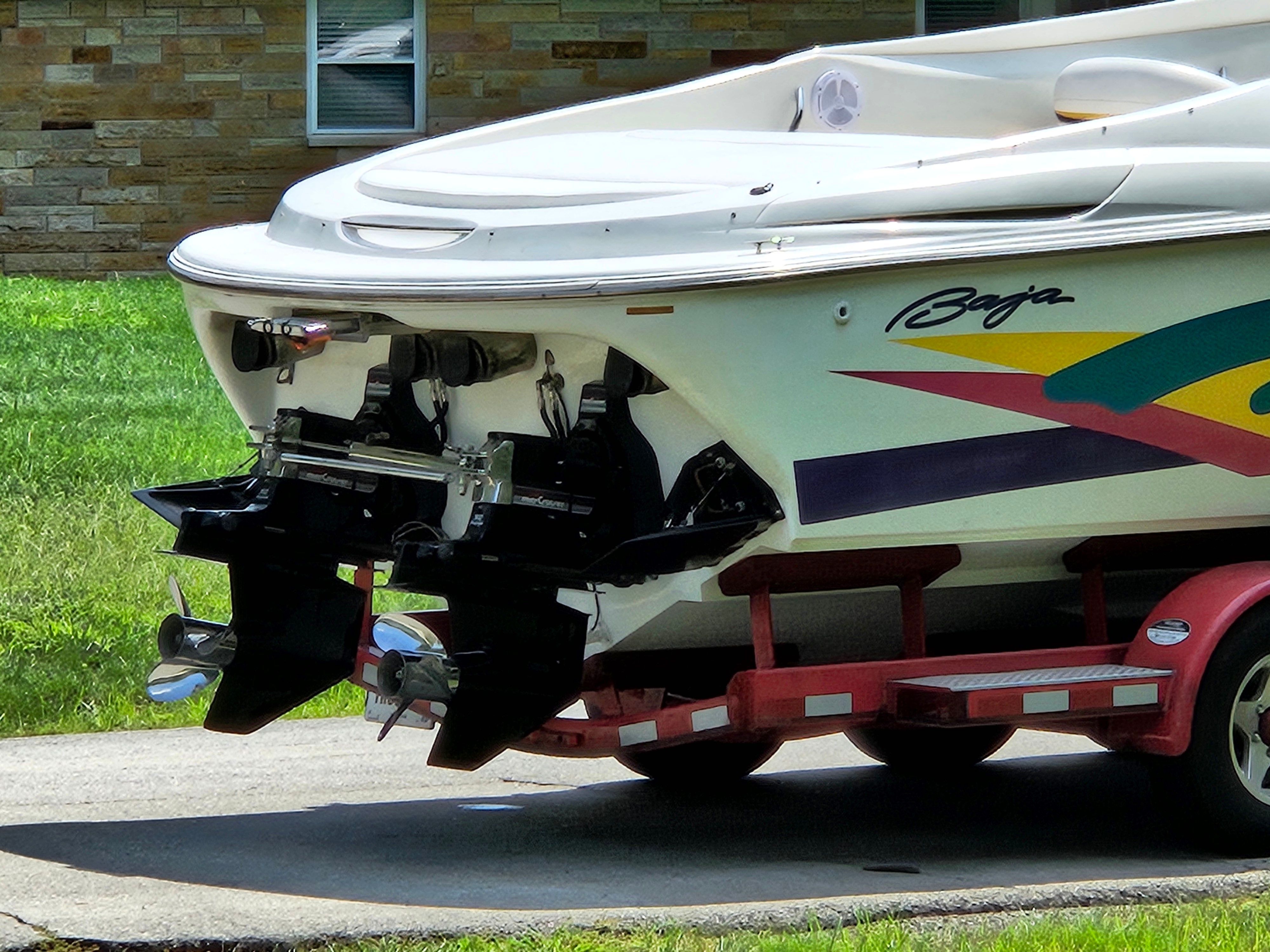 A 1996 Baja 302 Boss on a trailer, featuring colorful stripe design and twin outboard motors.