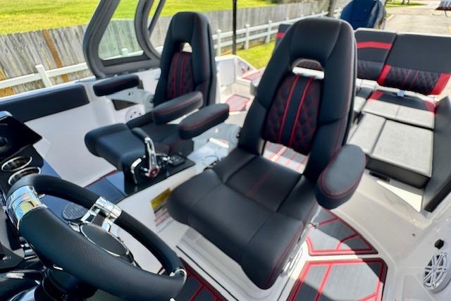 2026 Monterey Elite 25 OB boat interior with black and red seating and steering wheel.