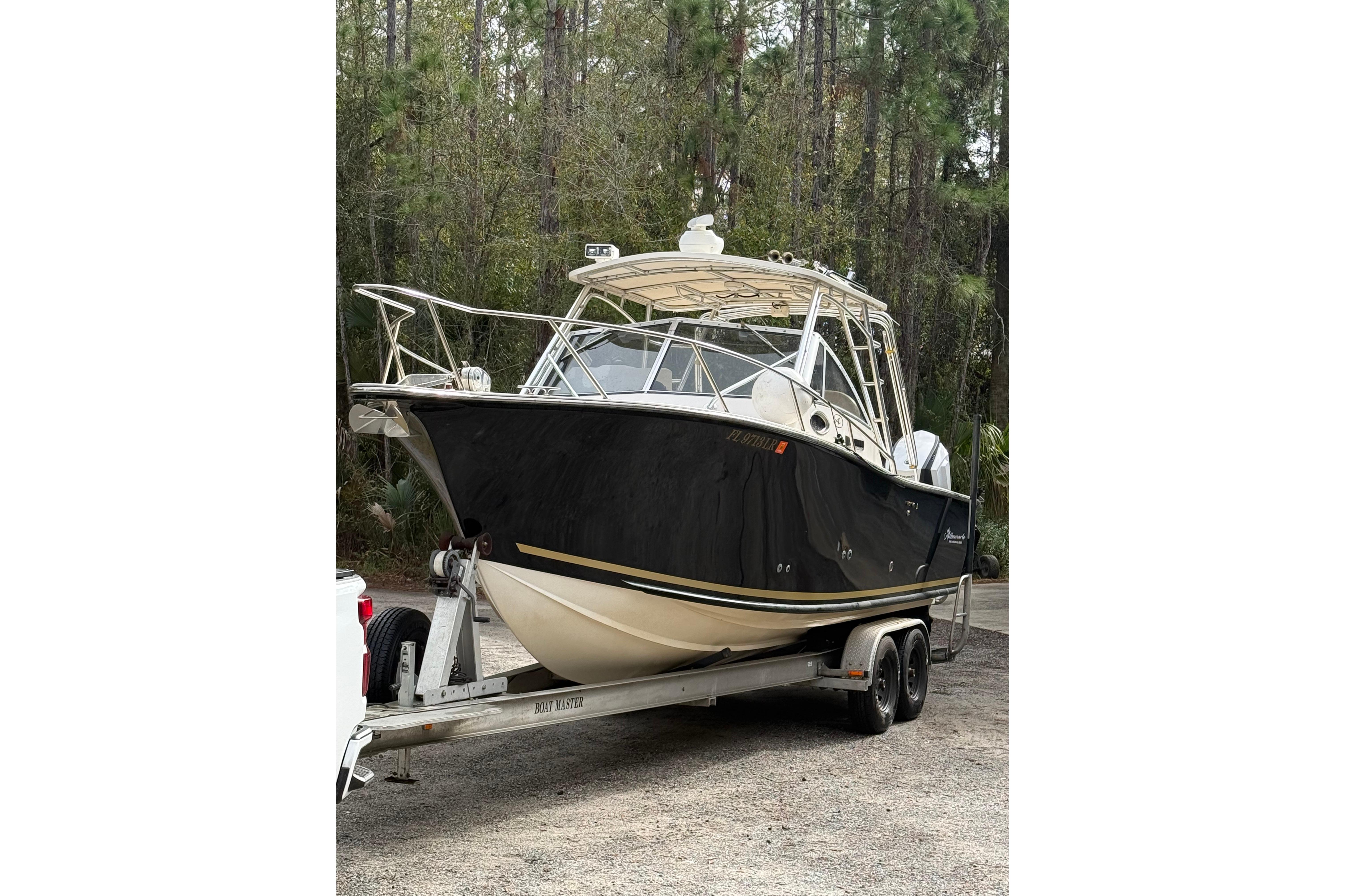 2002 Albemarle 265 Express Fisherman boat on trailer, parked in wooded area.