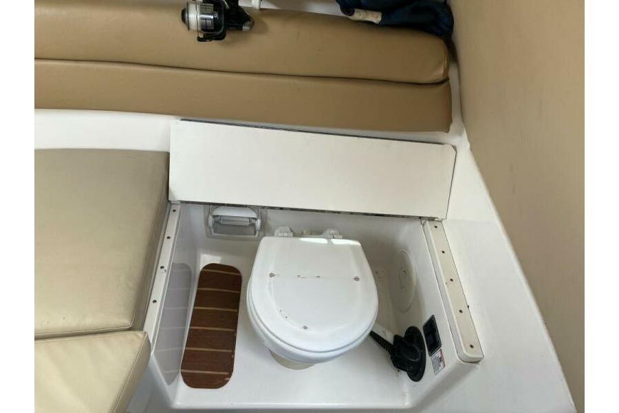 Interior of a 2006 Century 2400 Walk-Around boat featuring a compact marine toilet.