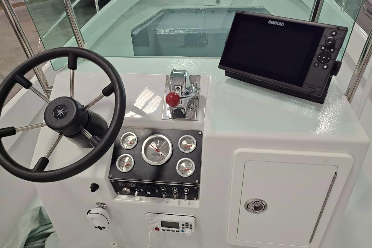 1975 Shamrock 200 Open boat dashboard with steering wheel, gauges, and Simrad navigation display.