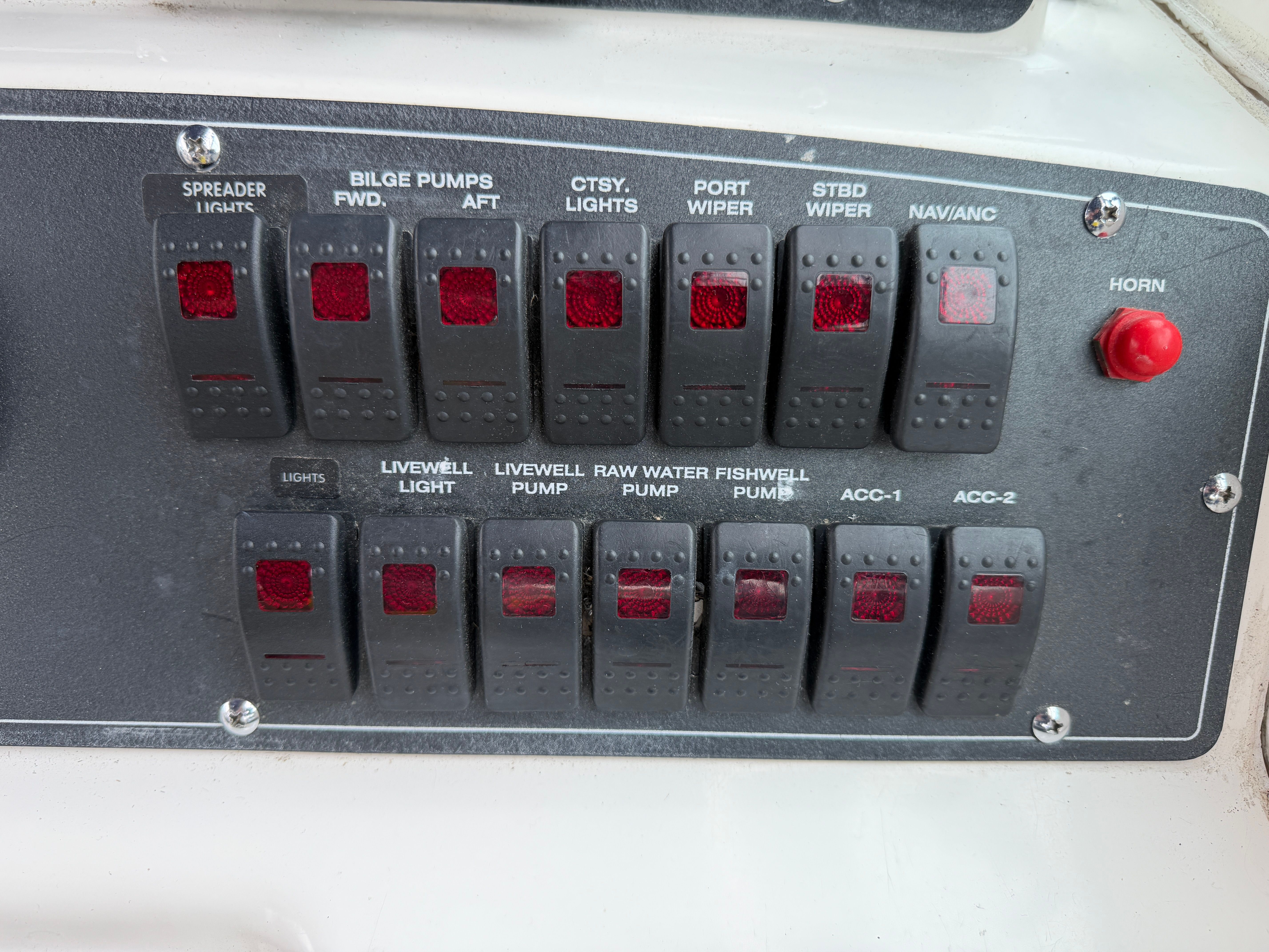 Control panel with various switches and indicator lights on a boat.
