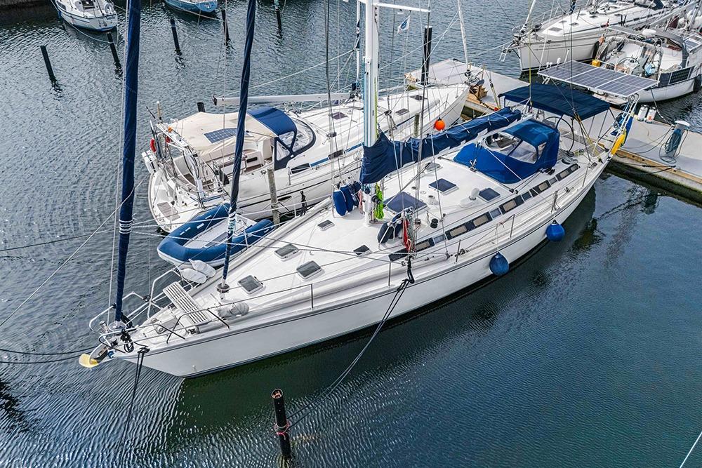 Sailboat Via 52, 1984 model, docked in marina with blue covers and fenders.