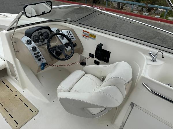 2006 Larson LXi 248 boat cockpit with steering wheel and white captain's chair.