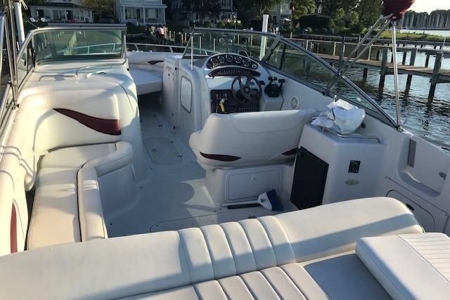 2004 Crownline 288 BR boat interior with white seating and dashboard, docked by the water.