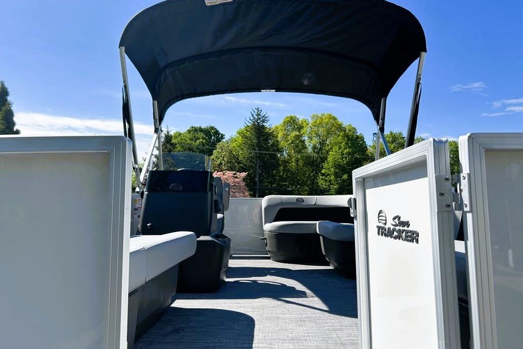 2026 Sun Tracker Party Barge 16 DLX pontoon boat with canopy, open seating, and scenic background.