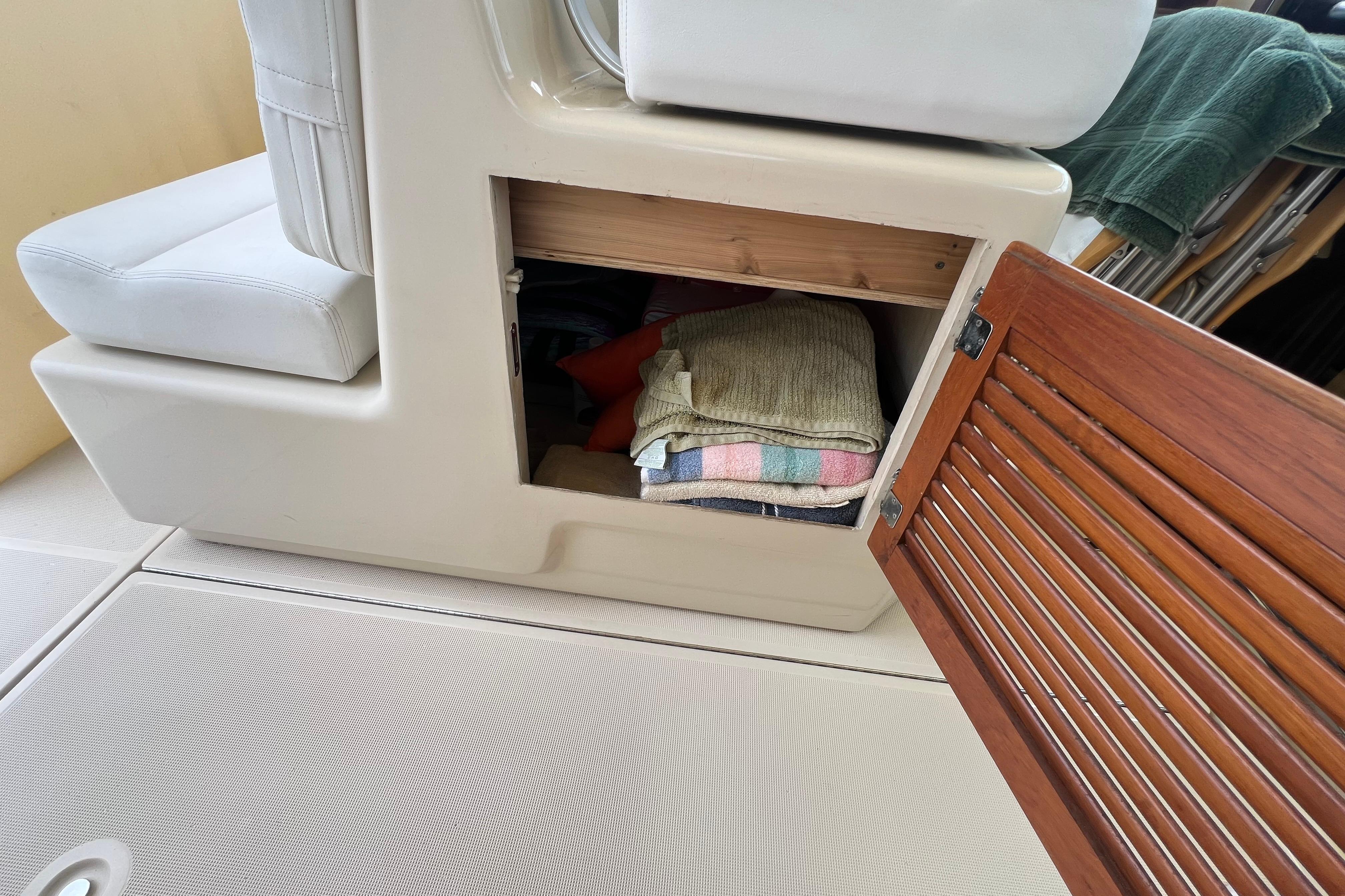 Storage compartment on a 1985 Tiara 36 OPEN boat with folded towels inside.